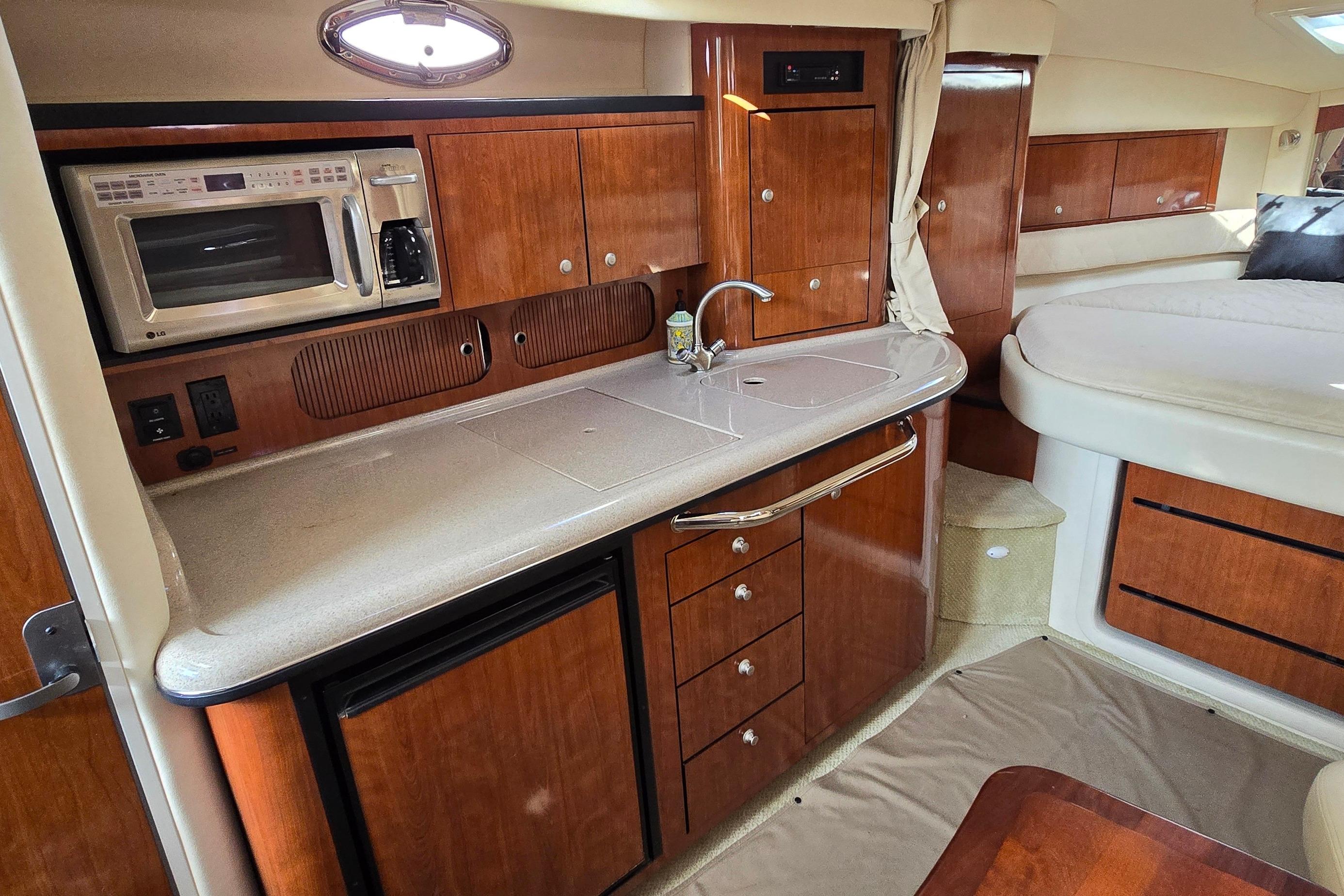 2007 Sea Ray 340 Sundancer interior with kitchenette, featuring wood cabinetry and modern appliances.
