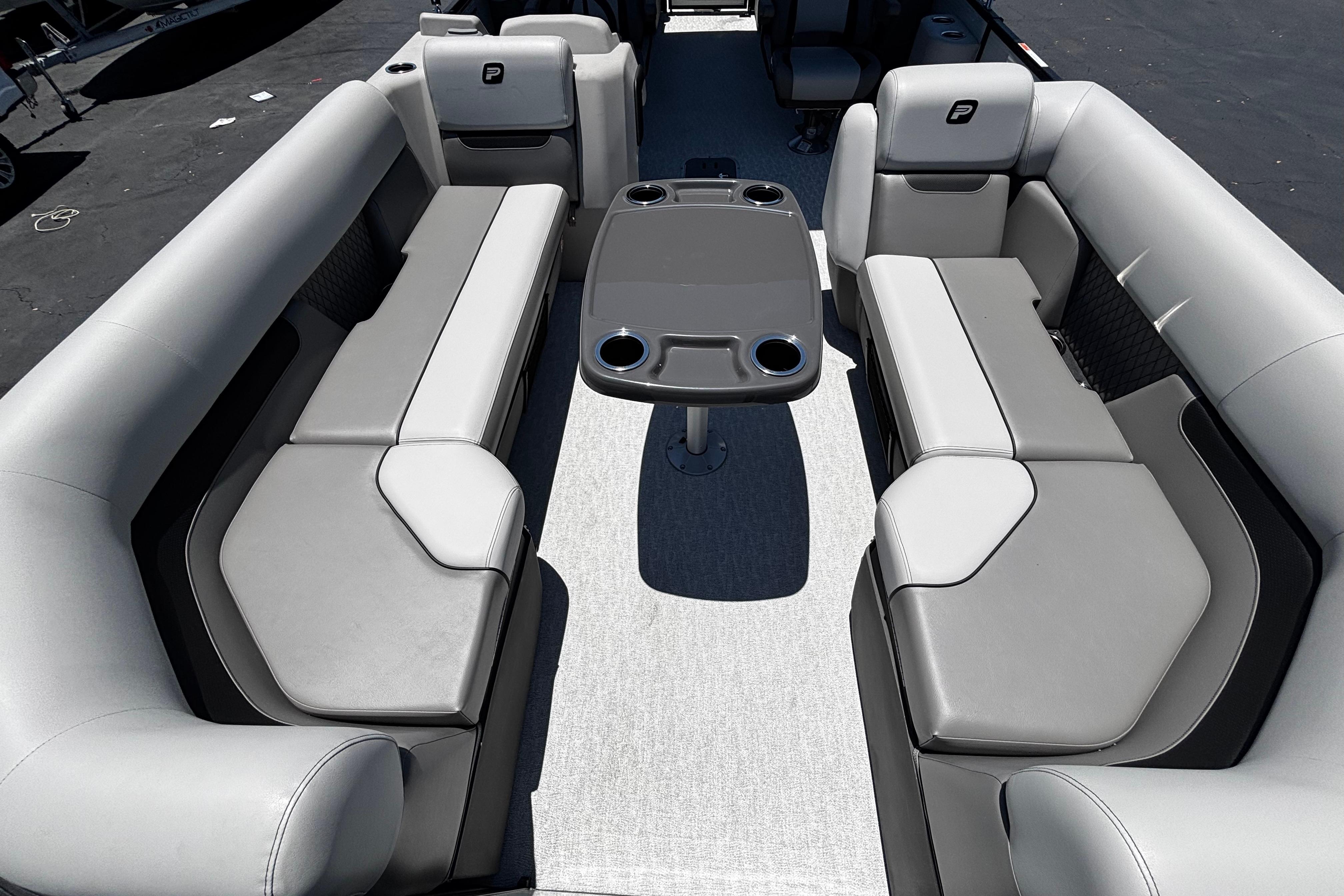 Luxurious seating area on 2026 Princecraft Vectra 23 QL pontoon boat with table and cup holders.