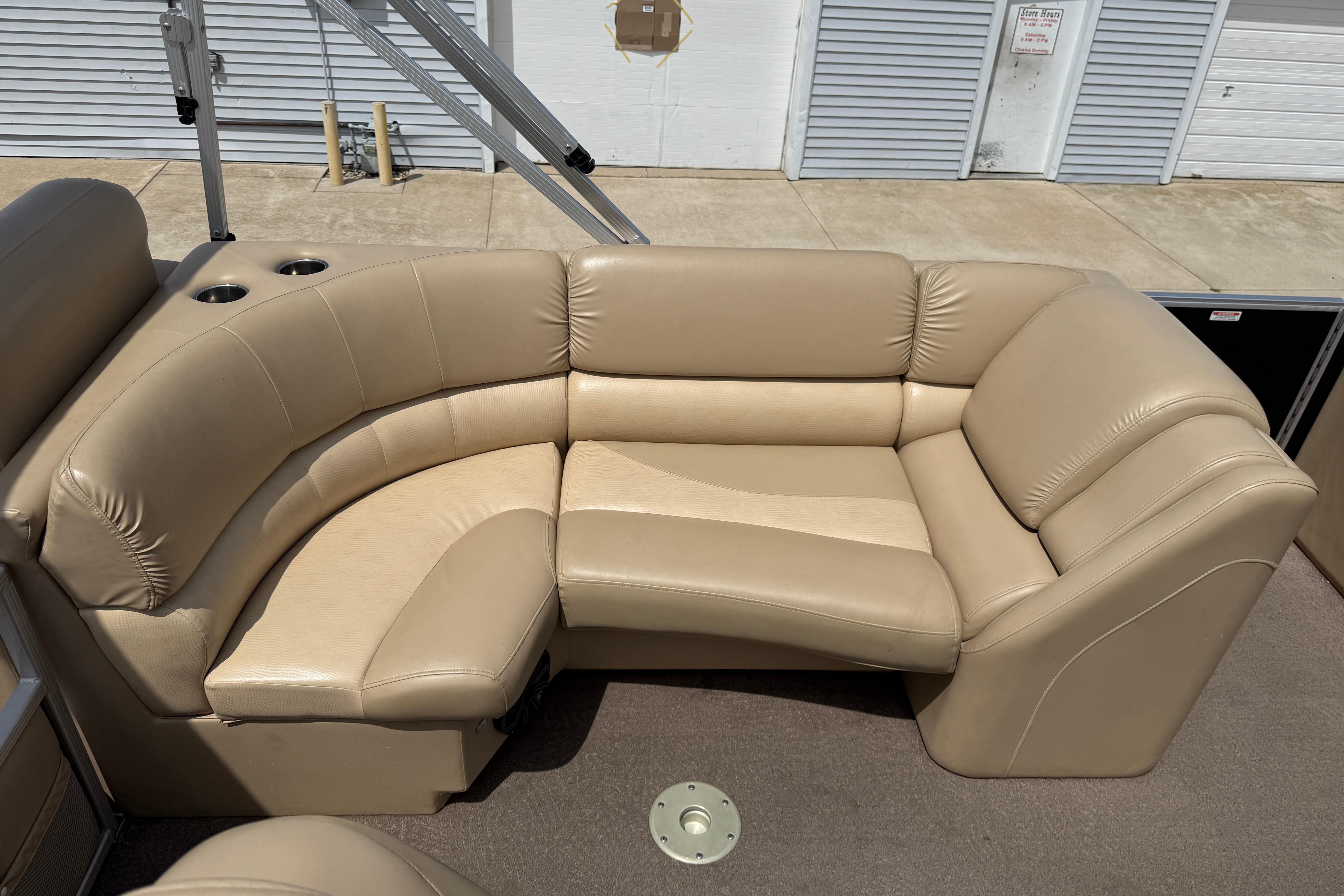 Beige leather seating on 2011 Bennington 2575QCW I/O boat, featuring cup holders and storage.