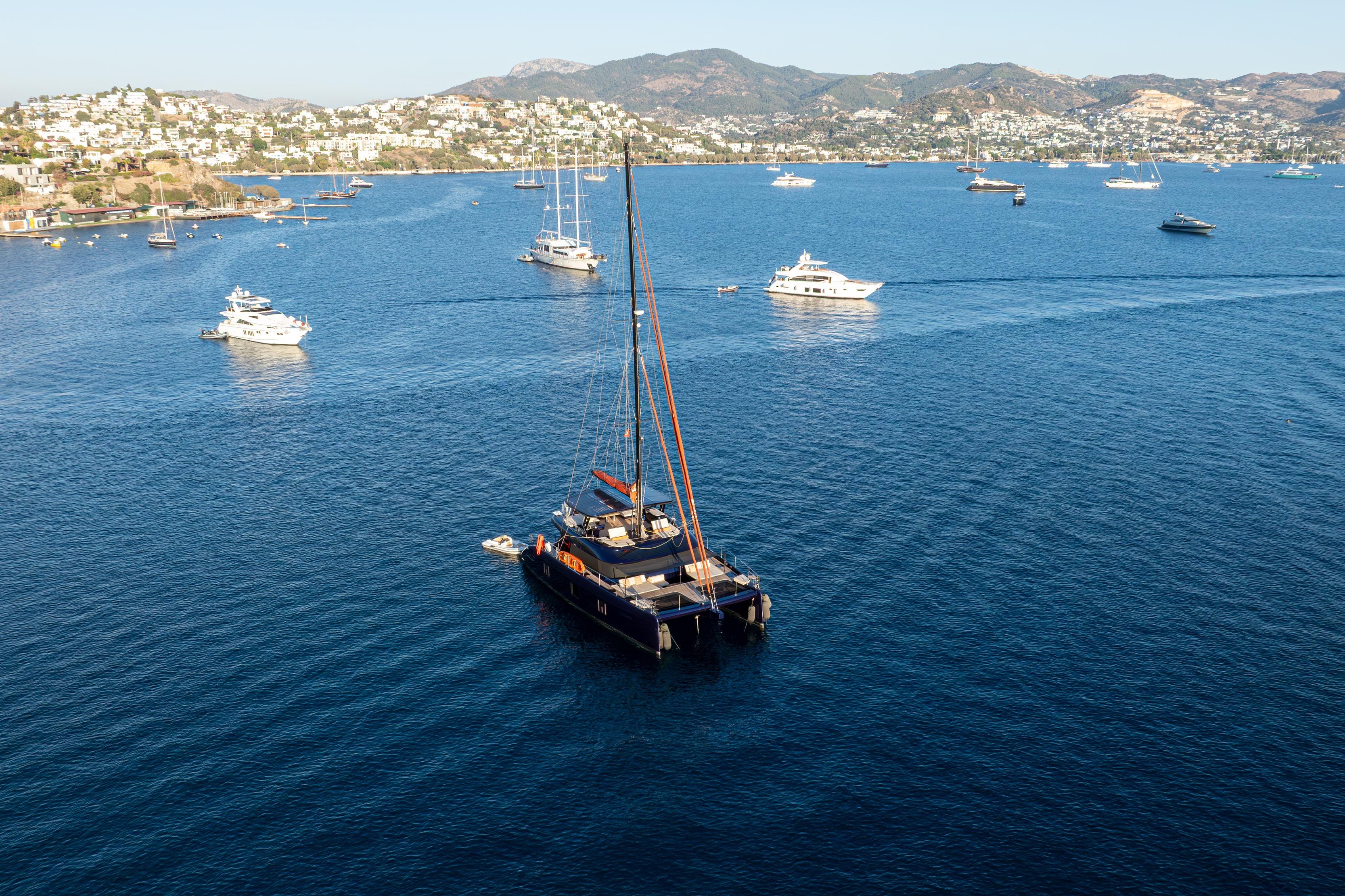 2024 Sunreef 60 Eco yacht sailing in a scenic bay with other boats.