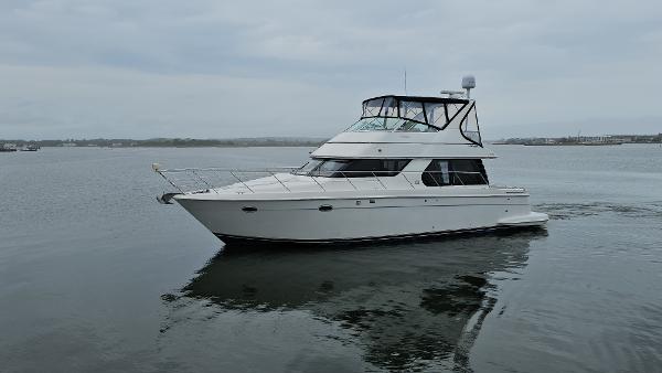 2000 Carver 450 Voyager Pilothouse yacht on calm water, overcast sky.