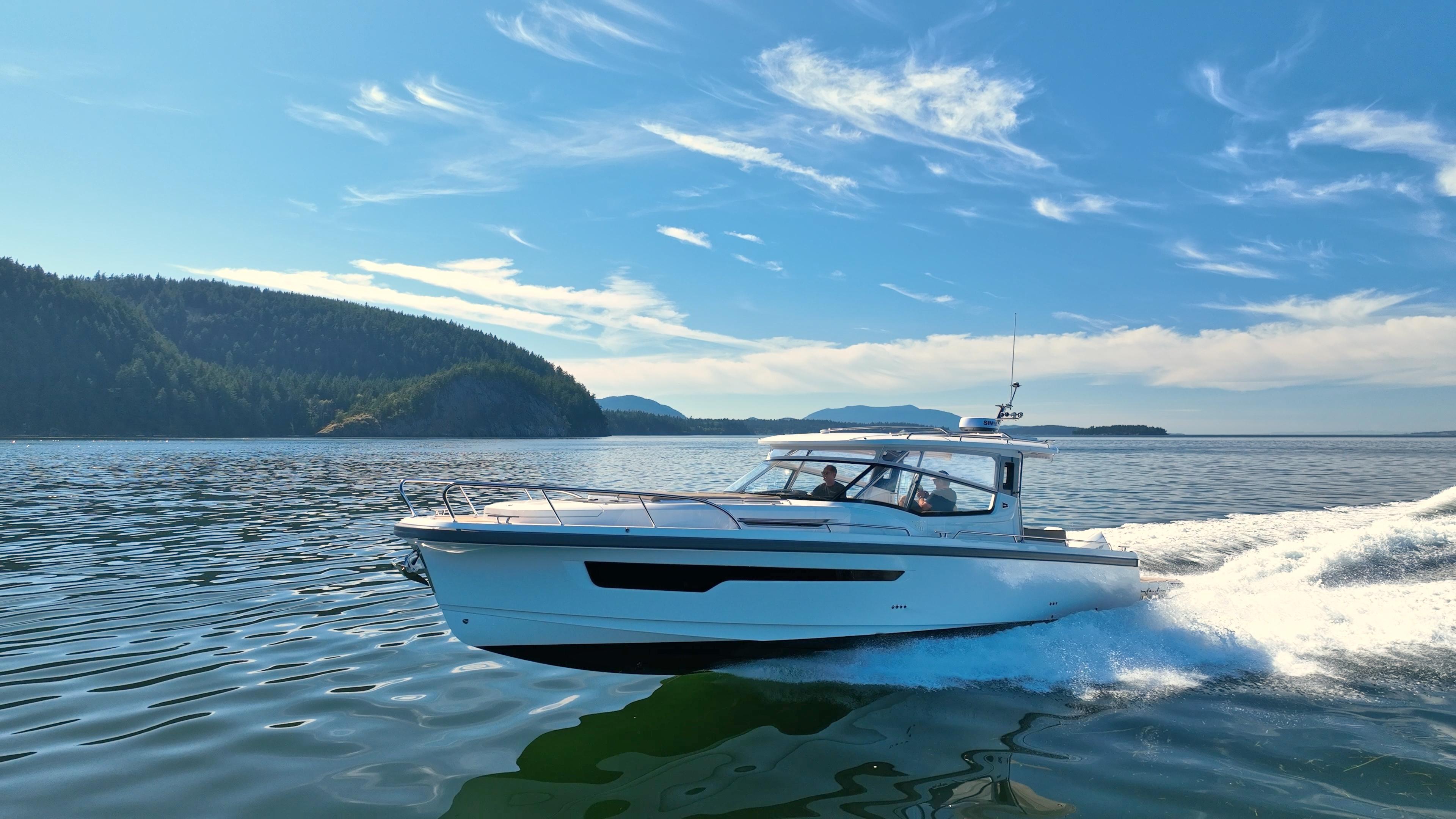2025 Nimbus W11 boat cruising on a sunny day, surrounded by scenic water and forested hills.