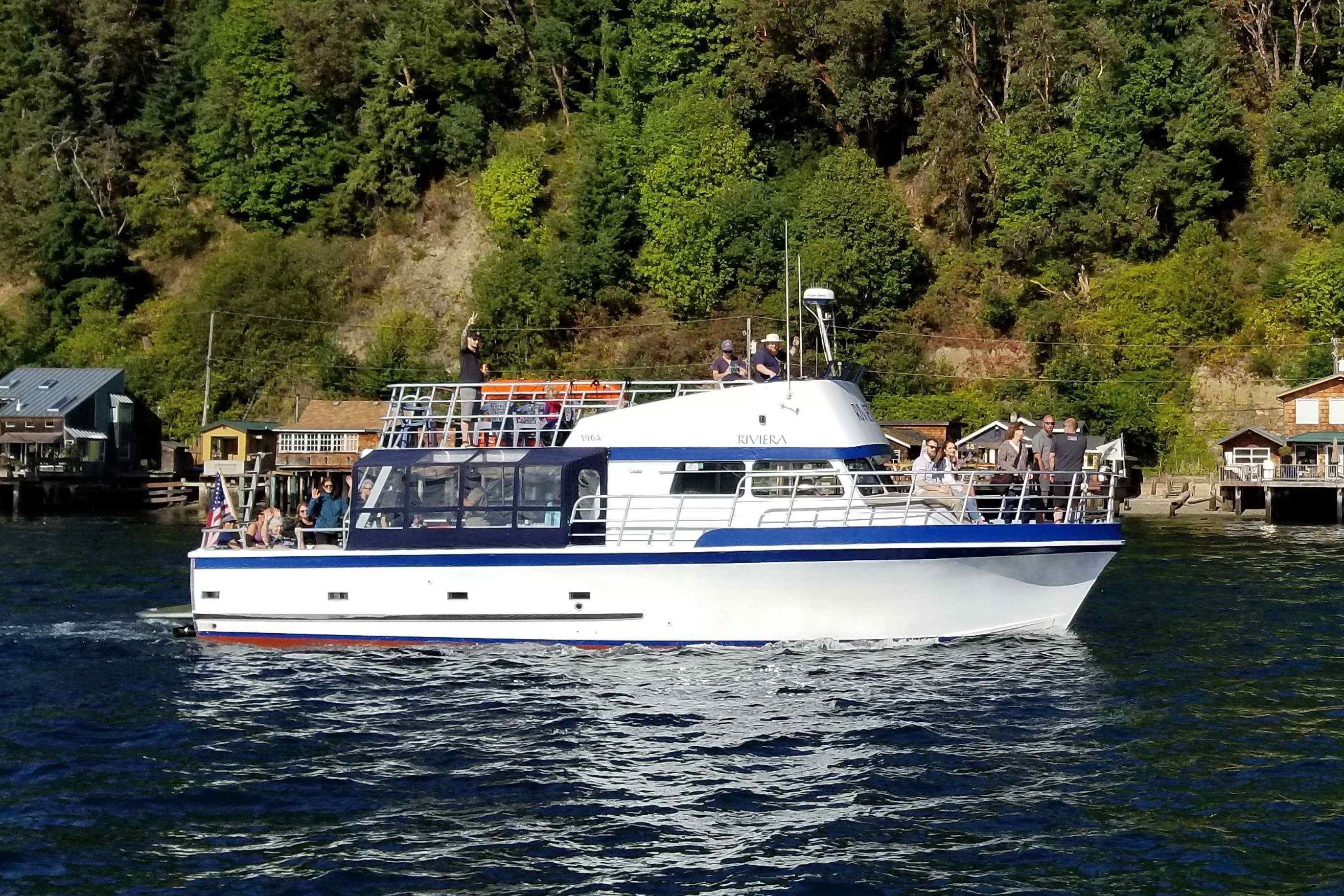 1964 Grandy Tour Boat cruising on a scenic waterway with lush green forest backdrop.