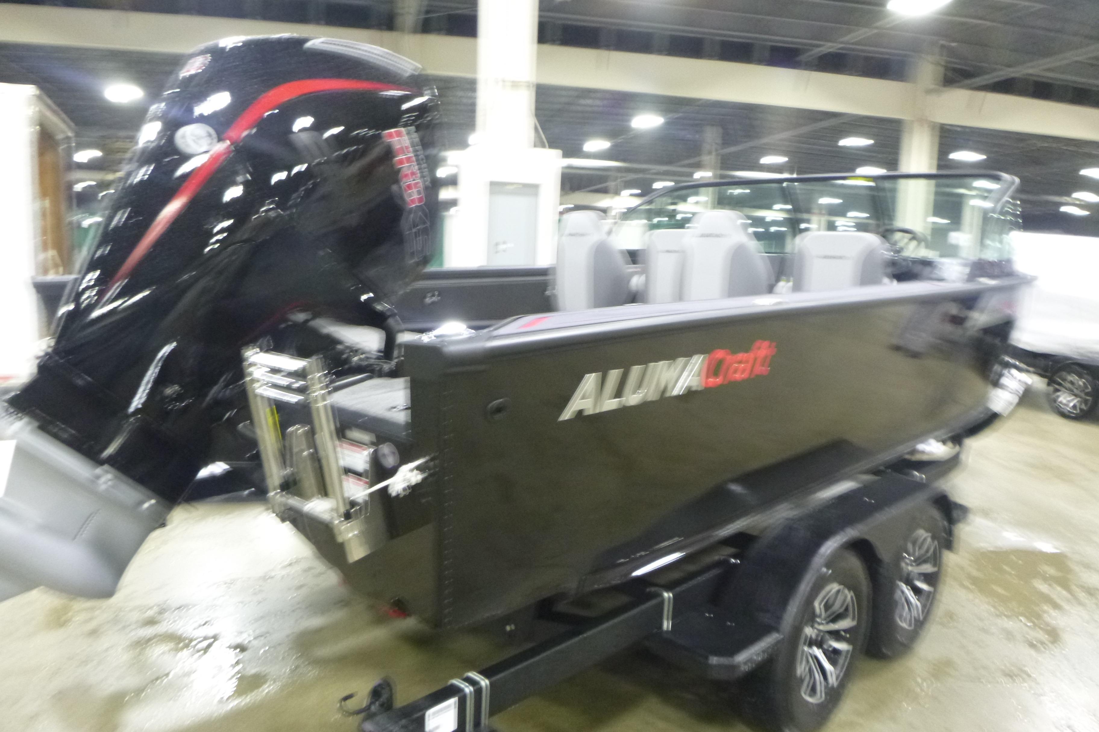 2026 Alumacraft Trophy 205X Sport boat with powerful outboard motor in showroom.