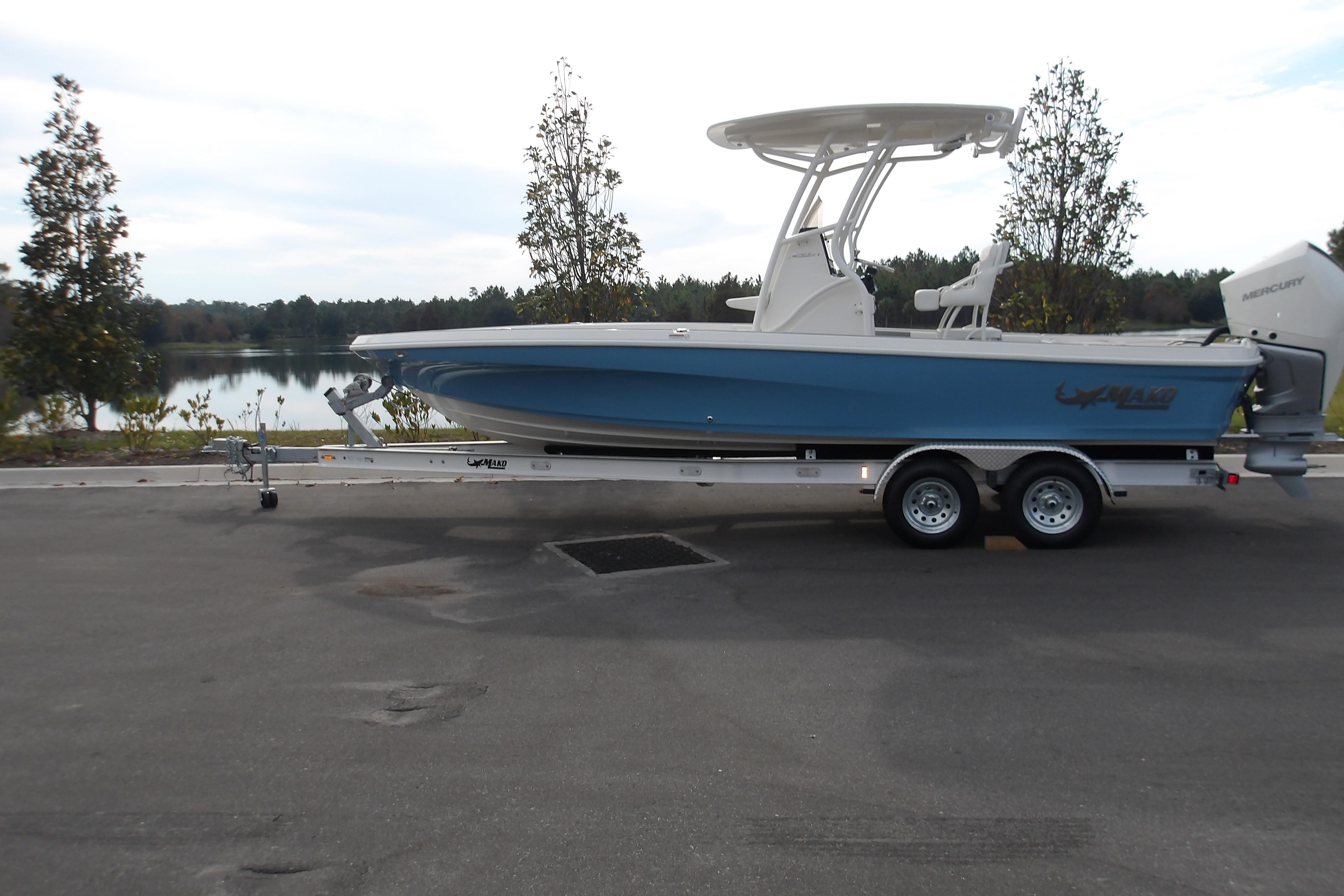 2026 Mako 24 APEX boat on trailer by a scenic lake.