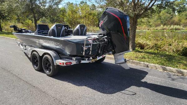 2025 Ranger ALPHA 208 boat on trailer, parked on a sunny road near trees.