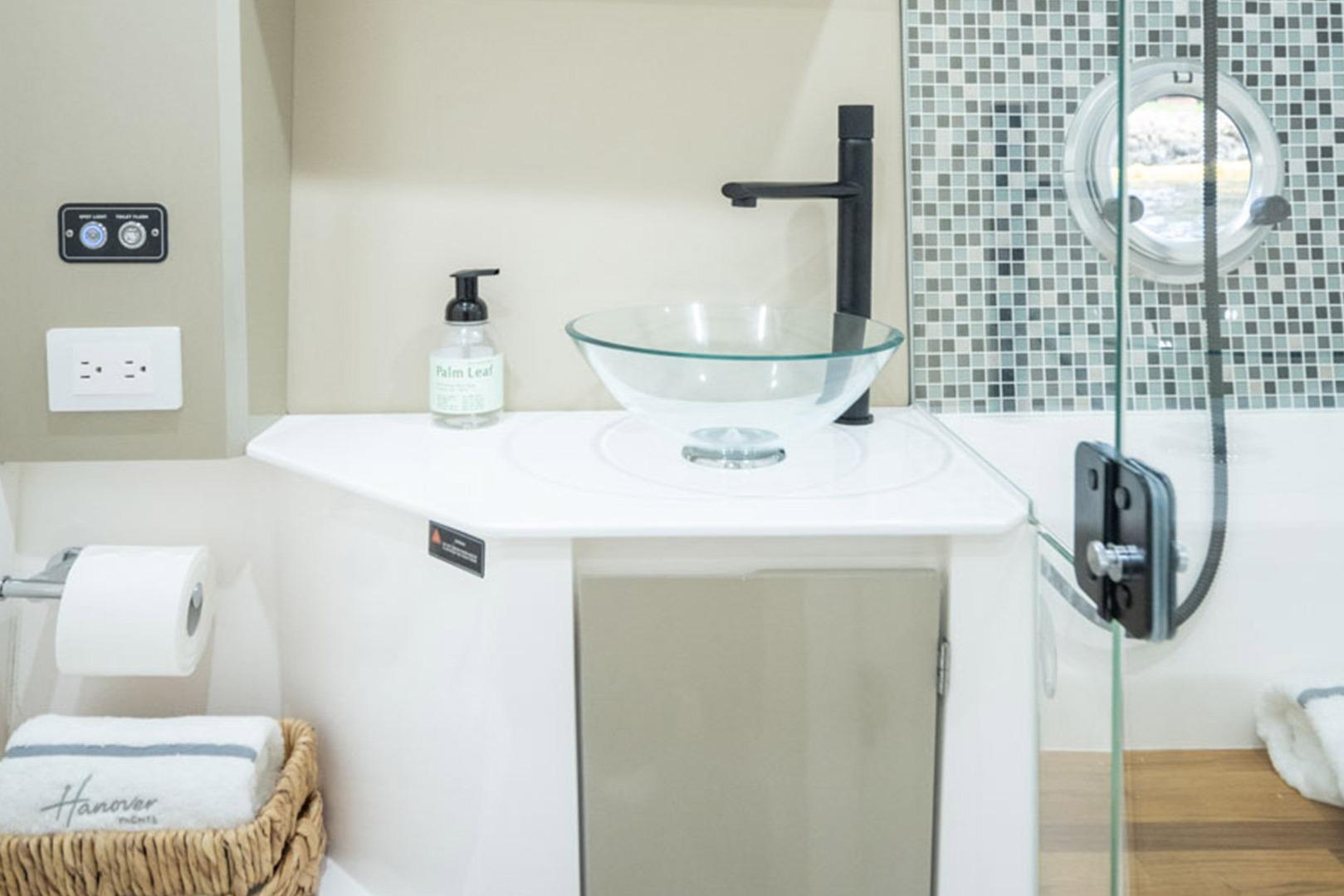 Modern bathroom in 2026 Hanover 387 RV with glass sink and mosaic tiles.