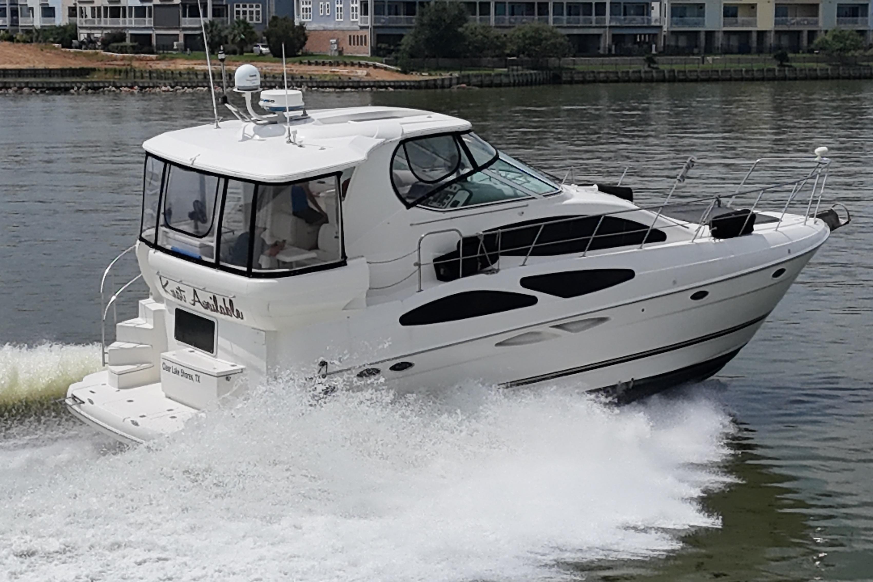 2004 Cruisers Yachts 405 Express Motoryacht cruising on a calm river near waterfront homes.