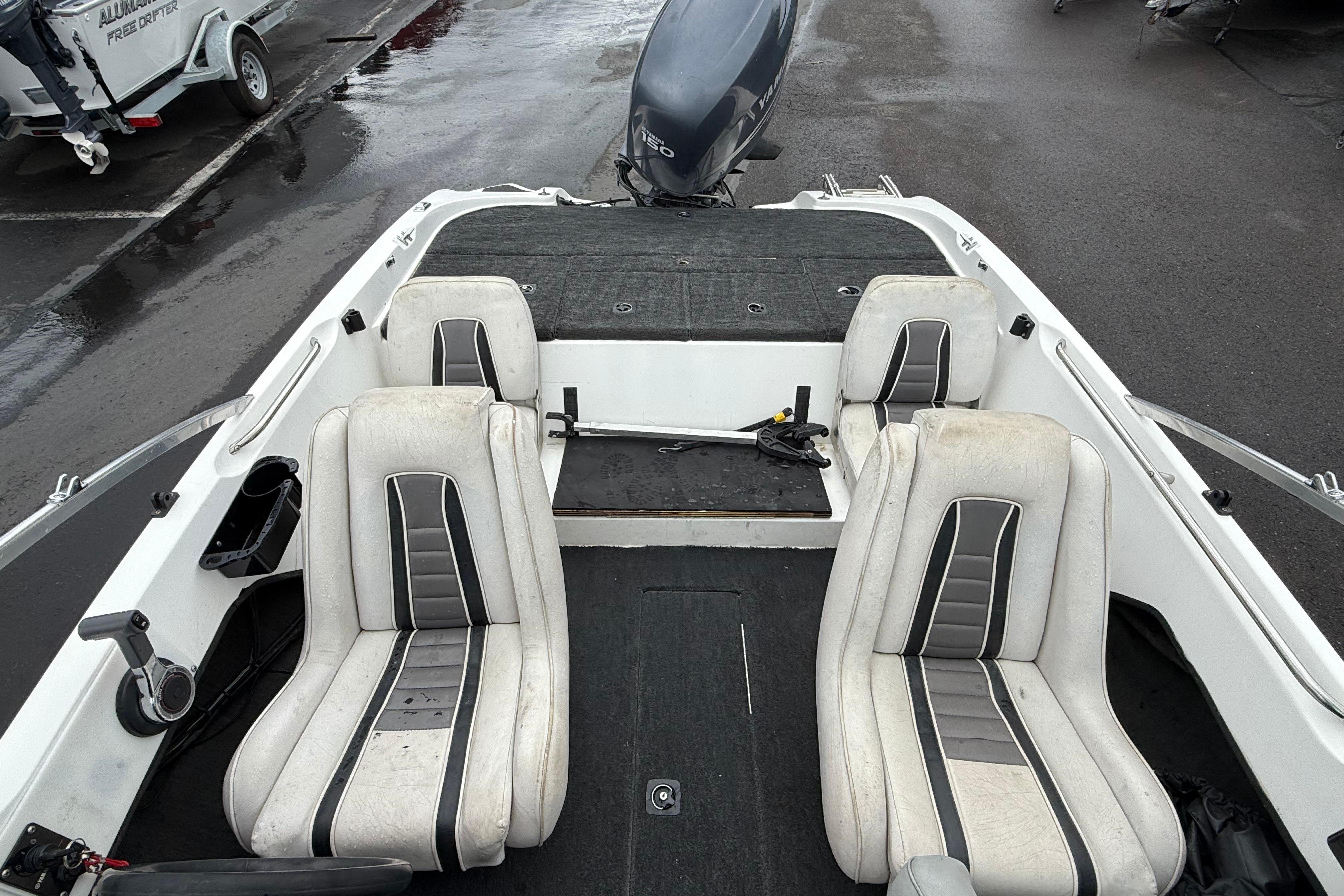 1996 Stratos 283 FS boat interior with dual seats and motor, parked on wet pavement.
