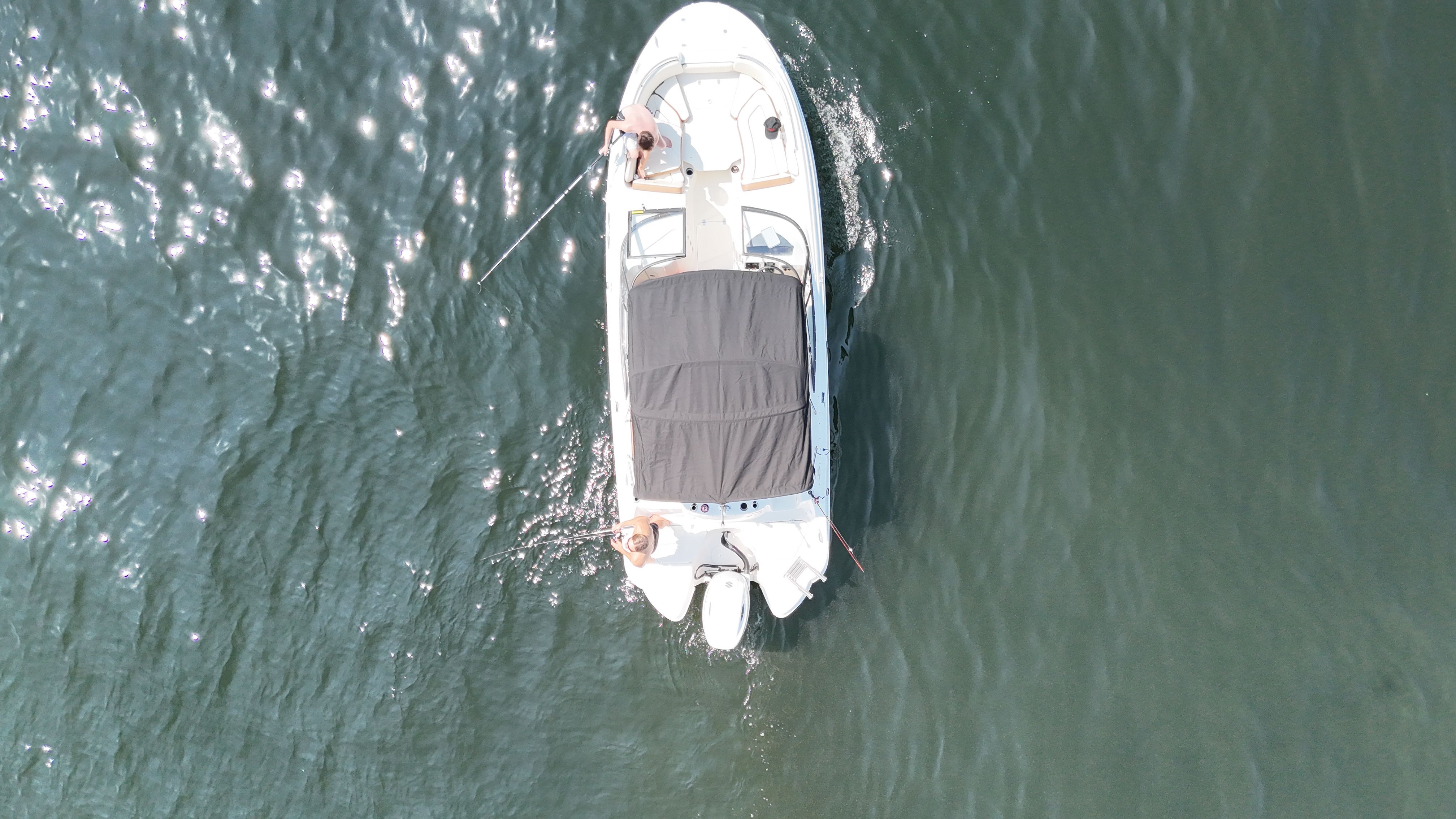A boat with a black canopy cruising on calm water.