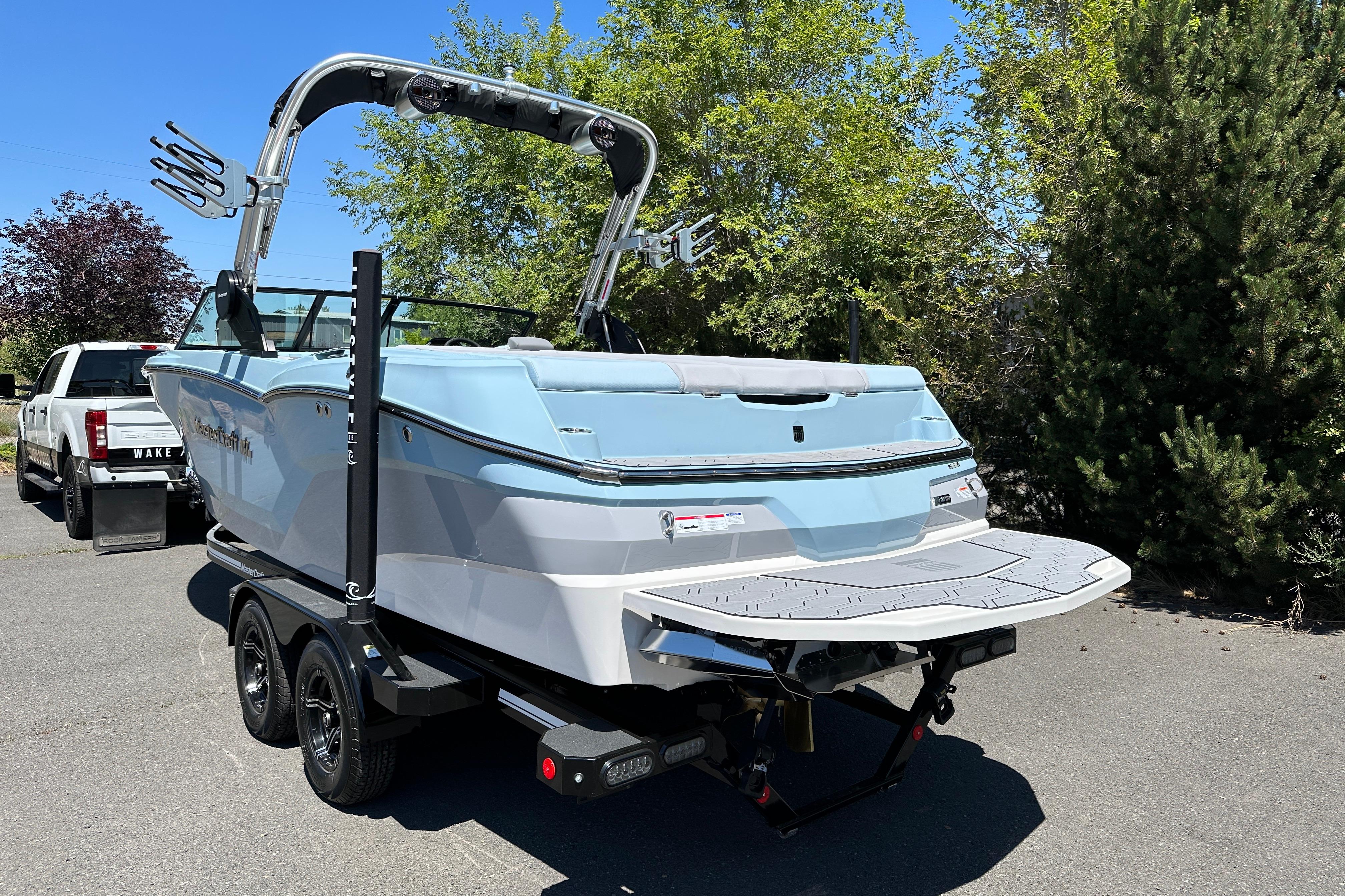 2023 MasterCraft NXT23 boat on trailer, parked outdoors, showcasing sleek design and swim platform.