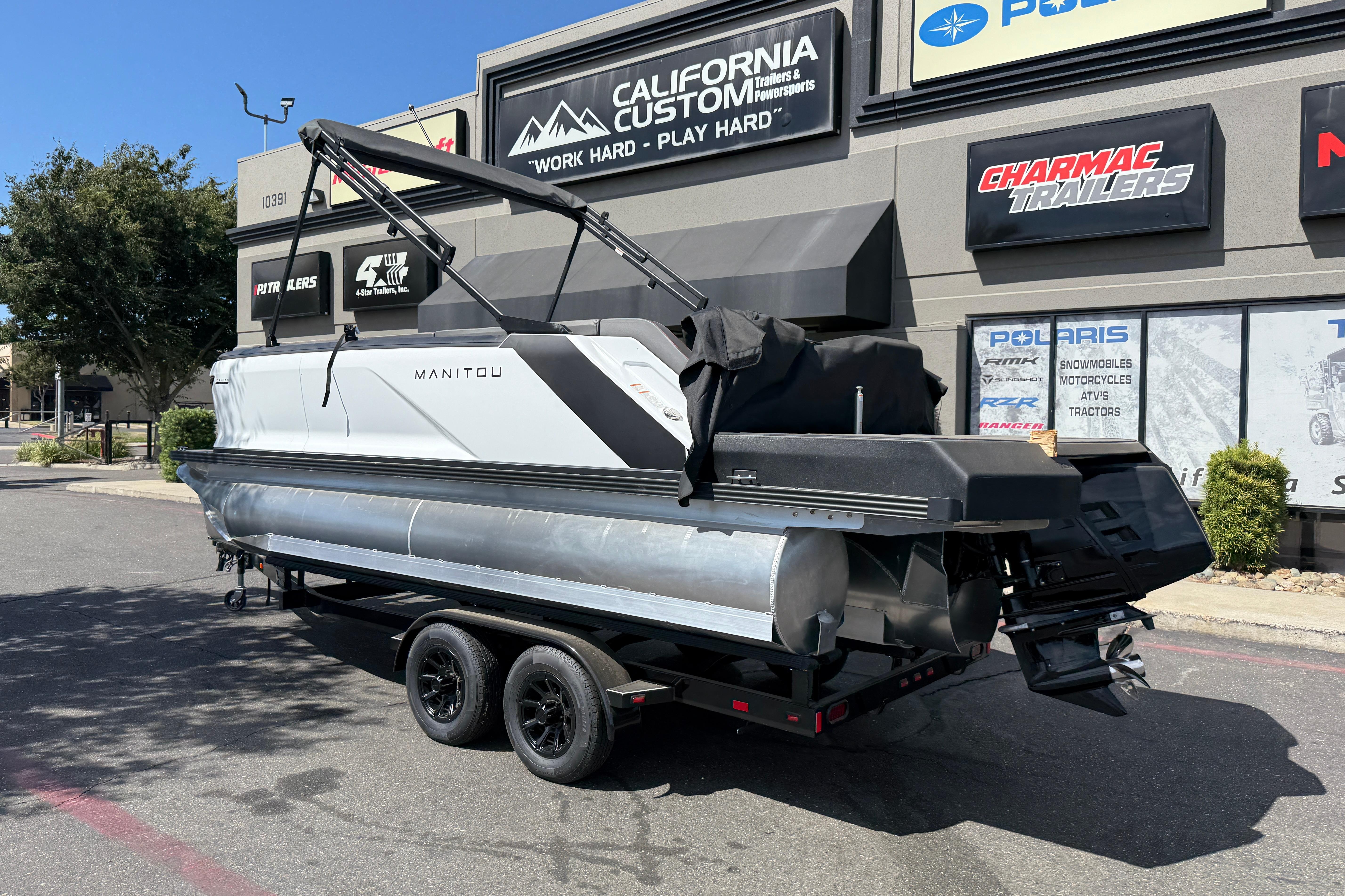 2025 Manitou Cruise pontoon boat on trailer outside dealership.
