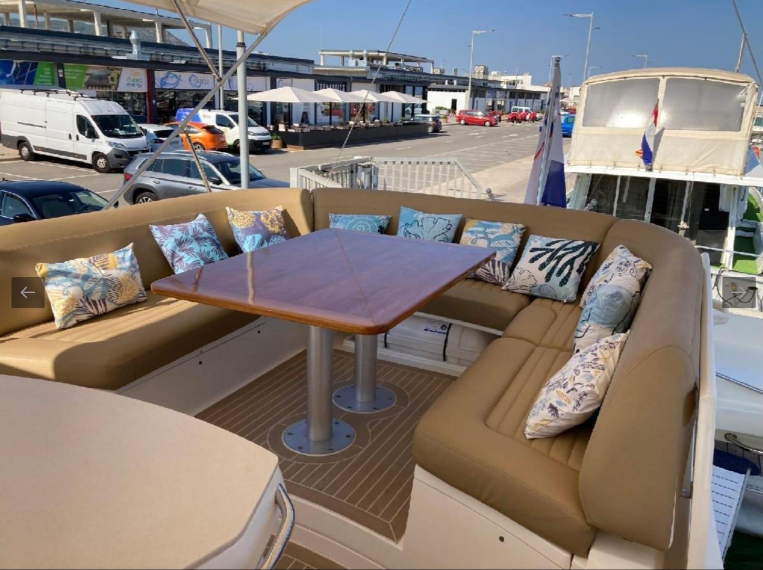 Luxurious seating area on a 2005 Sealine T60 yacht with decorative cushions and wooden table.
