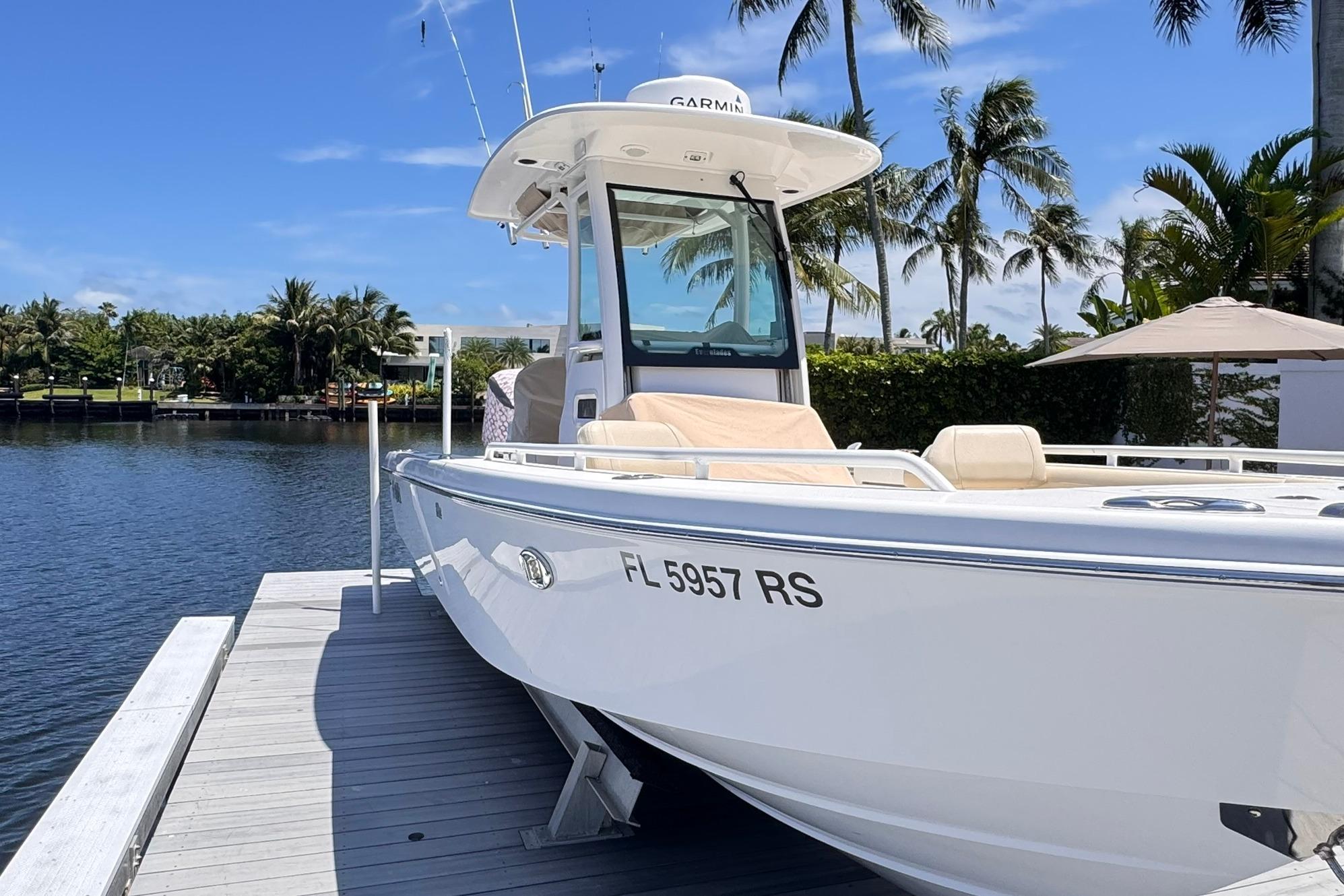 2018 Everglades 253 Center Console boat docked by tropical waterfront.