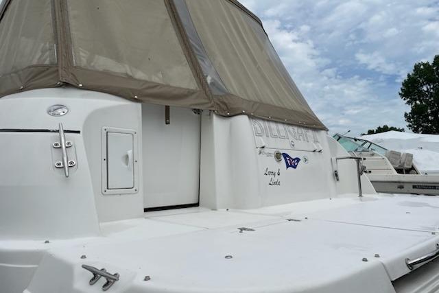 2002 Cruisers Yachts 3372 Express boat with beige canopy, docked under cloudy sky.