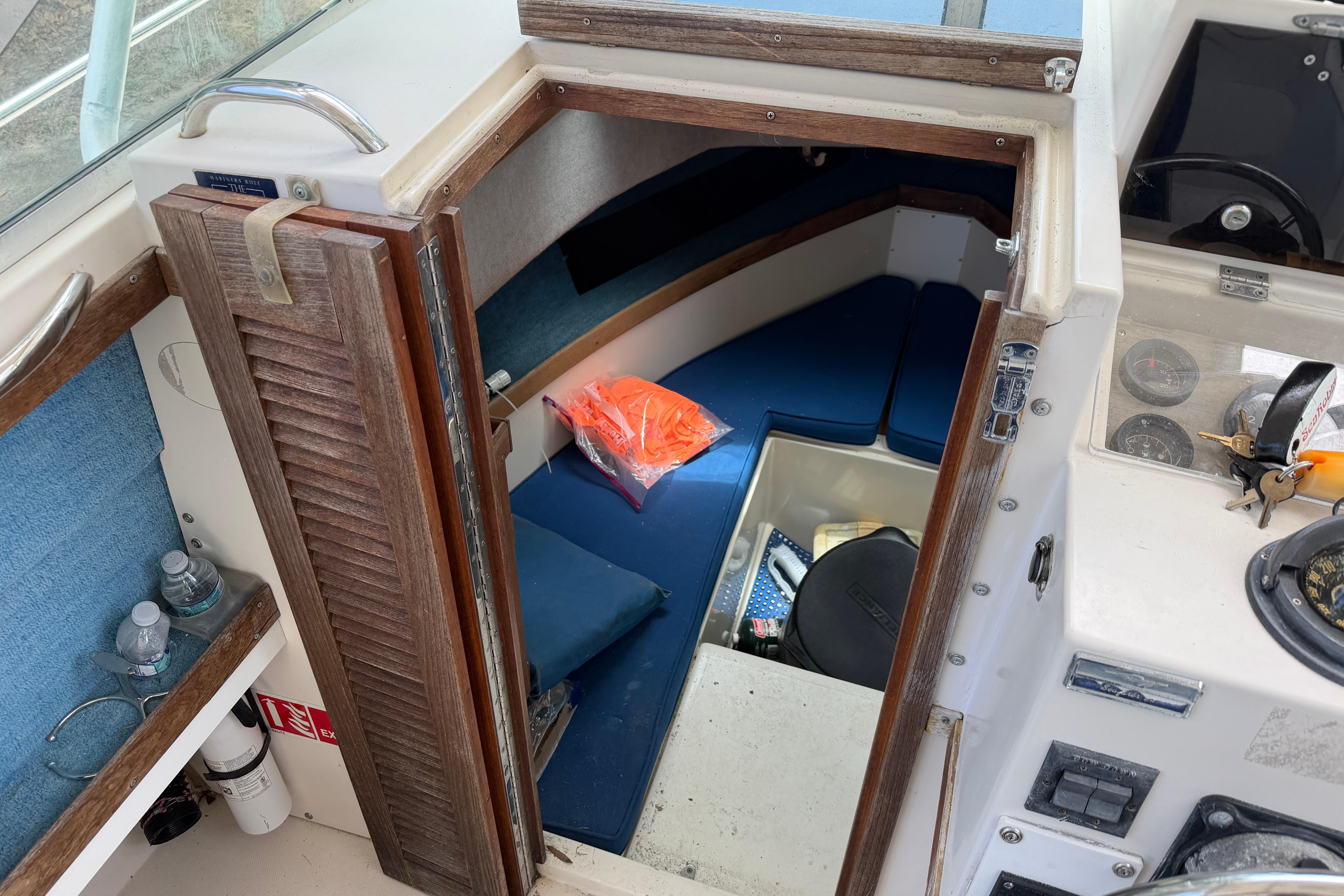 Interior cabin of a 1987 Grady-White Seafarer 226 boat with blue seating and storage.