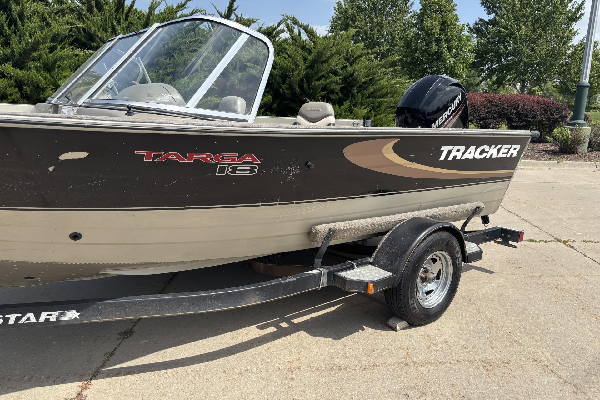 1999 Tracker Targa 18 boat on trailer, parked outdoors with trees in background.