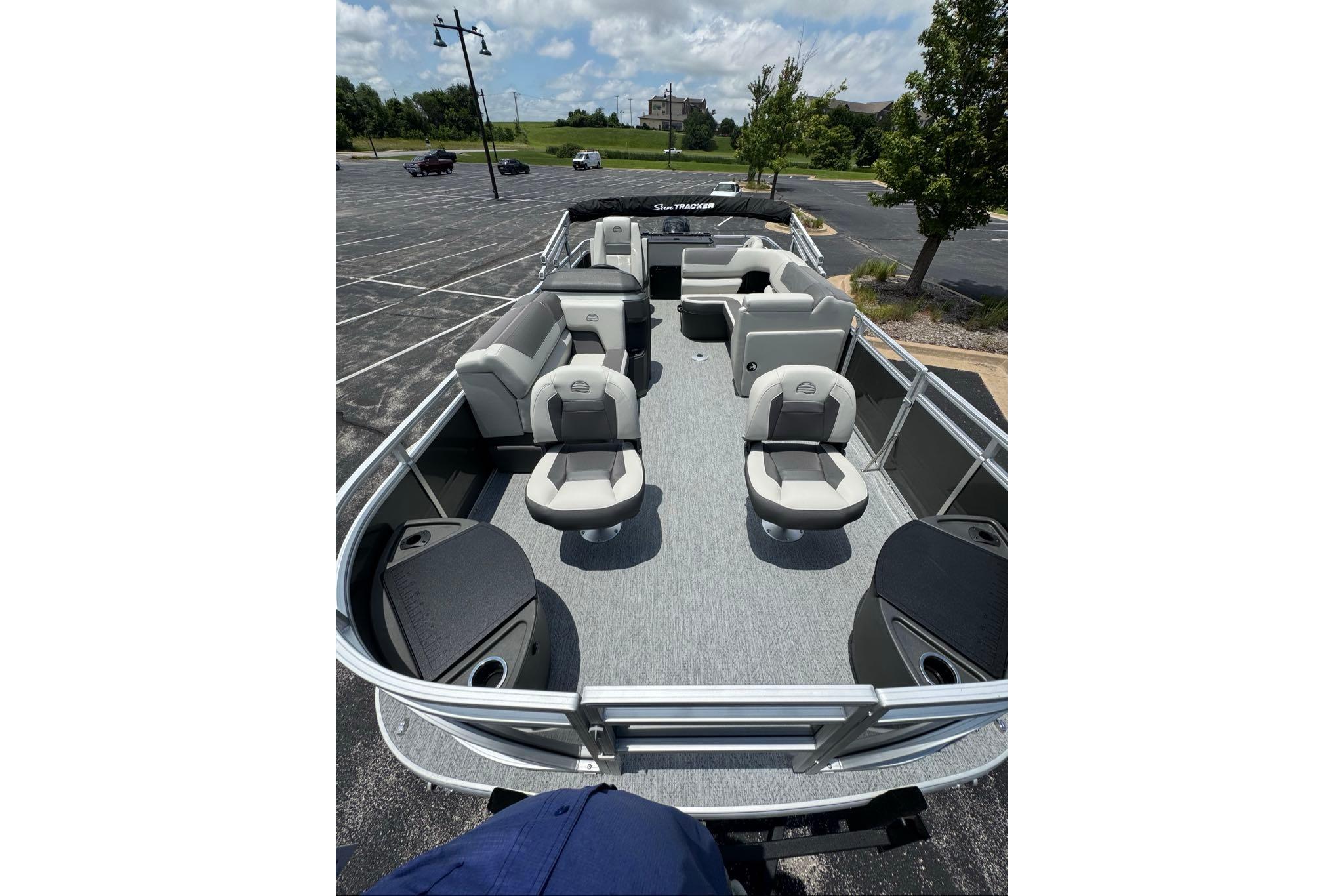2026 Sun Tracker Fishin' Barge 20 DLX pontoon boat with spacious seating in a parking lot.