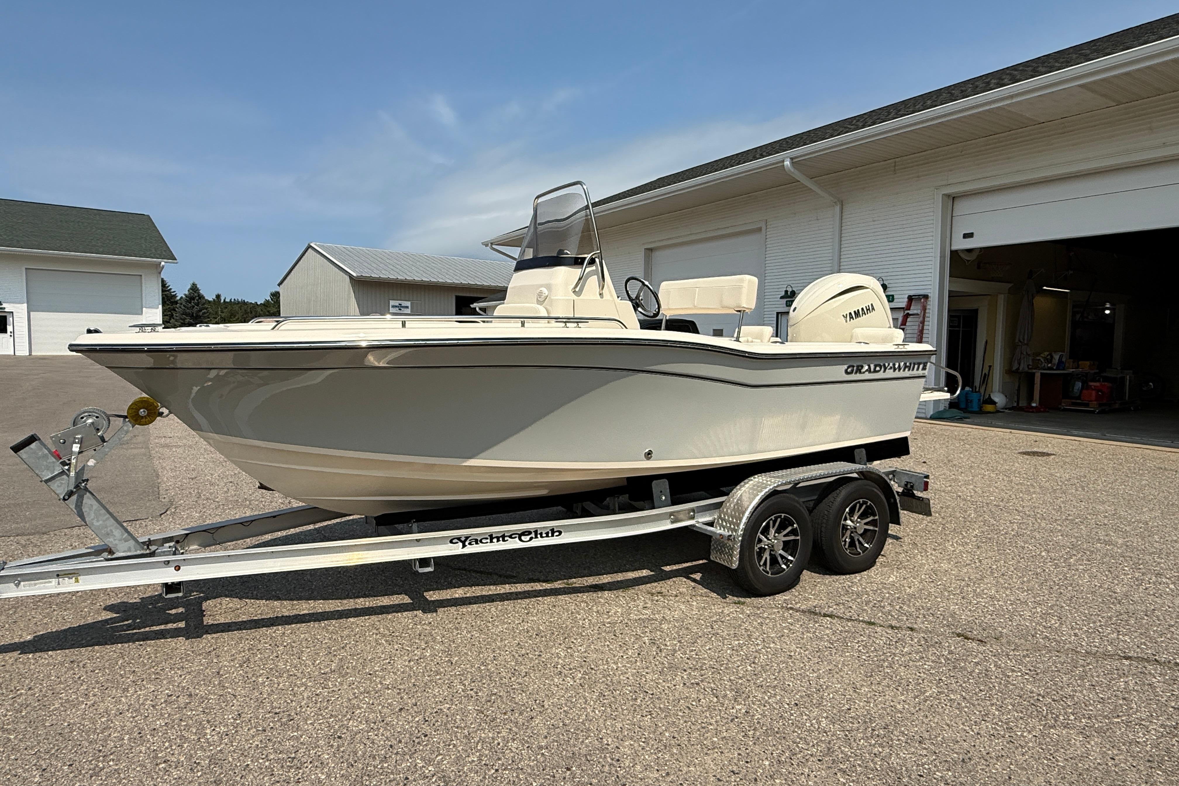 2025 Grady-White Fisherman 180 boat on trailer, parked outside a garage.