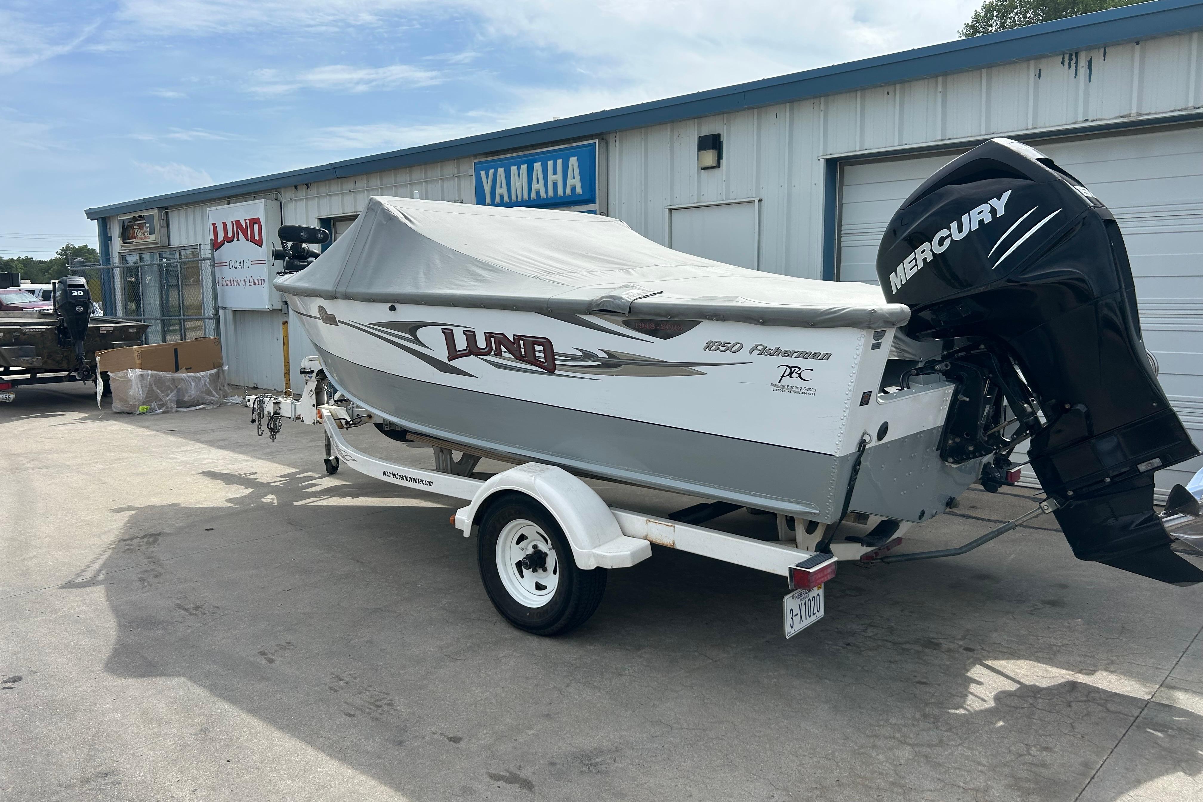 2008 Lund 1850 Fisherman boat with Mercury engine, parked outside a Yamaha dealership.