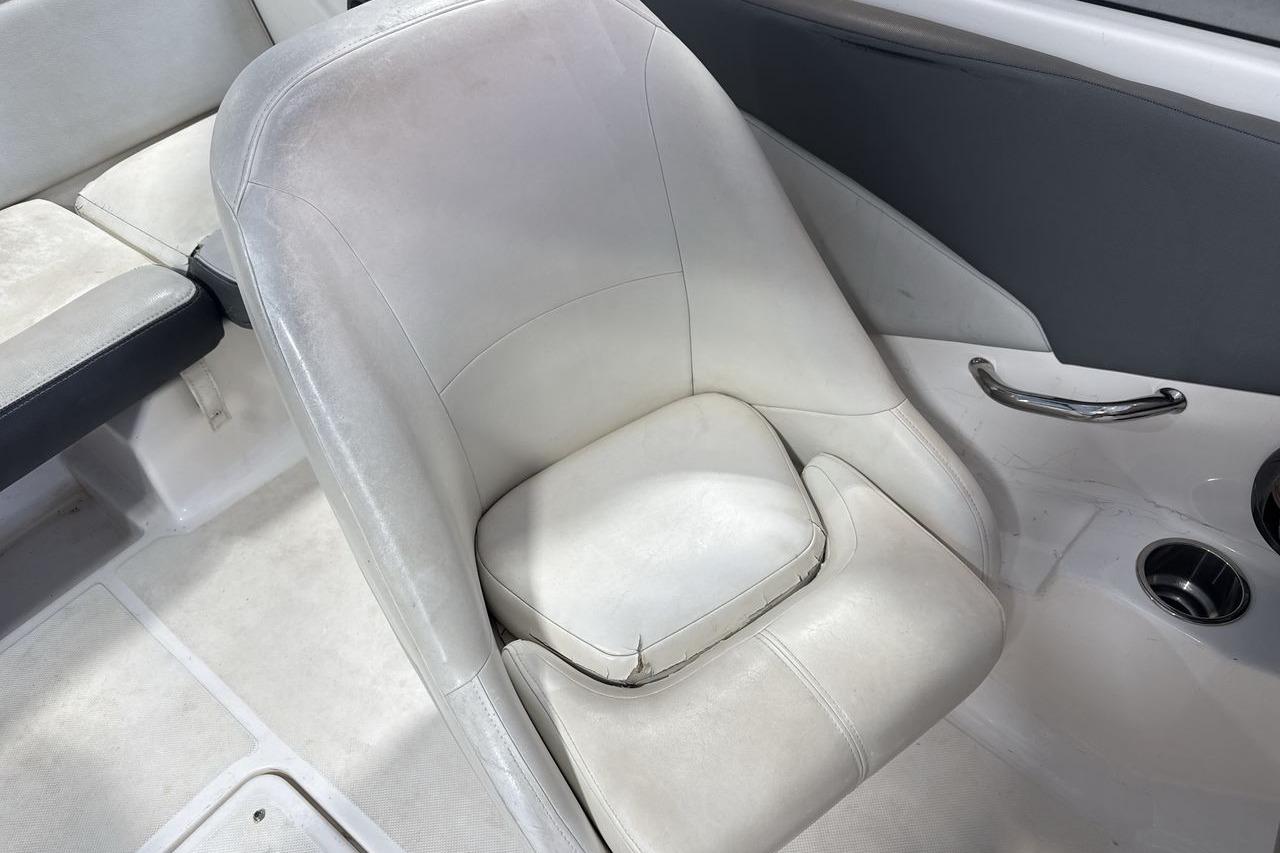 White interior seating of a 2012 Regal 1900 Bowrider boat, featuring cup holders and armrest.