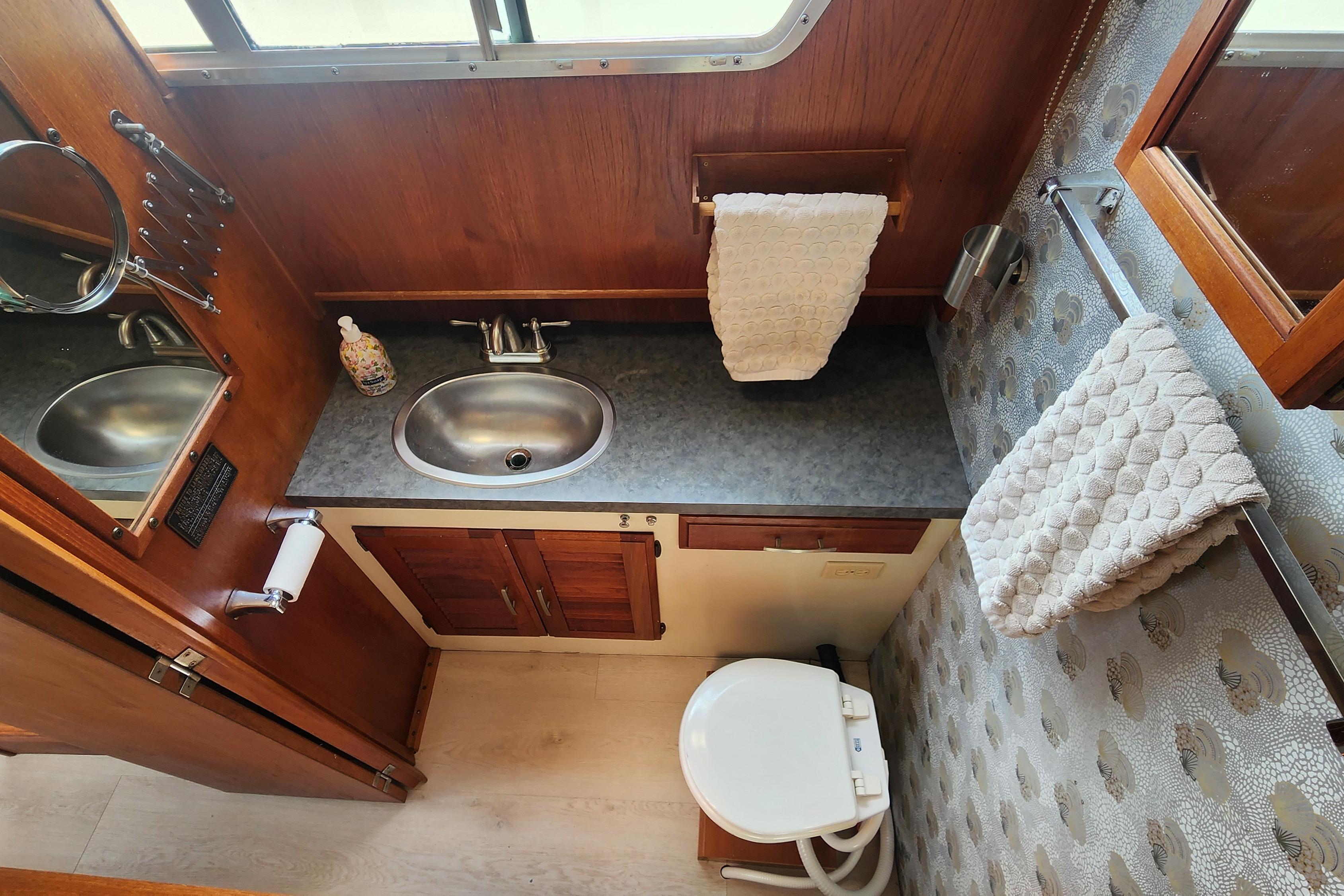 1981 Tollycraft 43 yacht bathroom with sink, toilet, and wooden cabinetry.