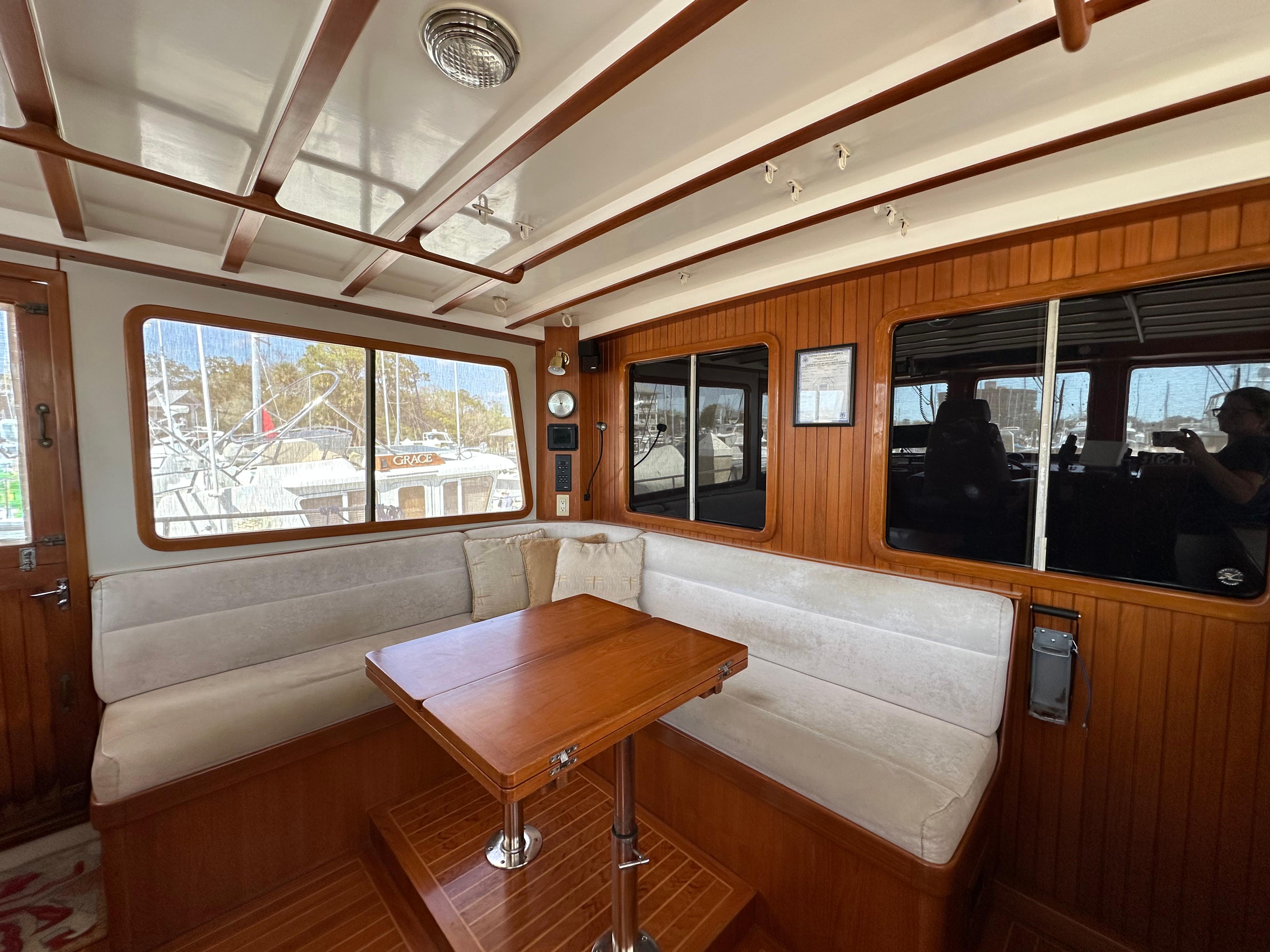 Interior of 1997 Kadey-Krogen 48 Whaleback yacht with wooden dining area and windows.