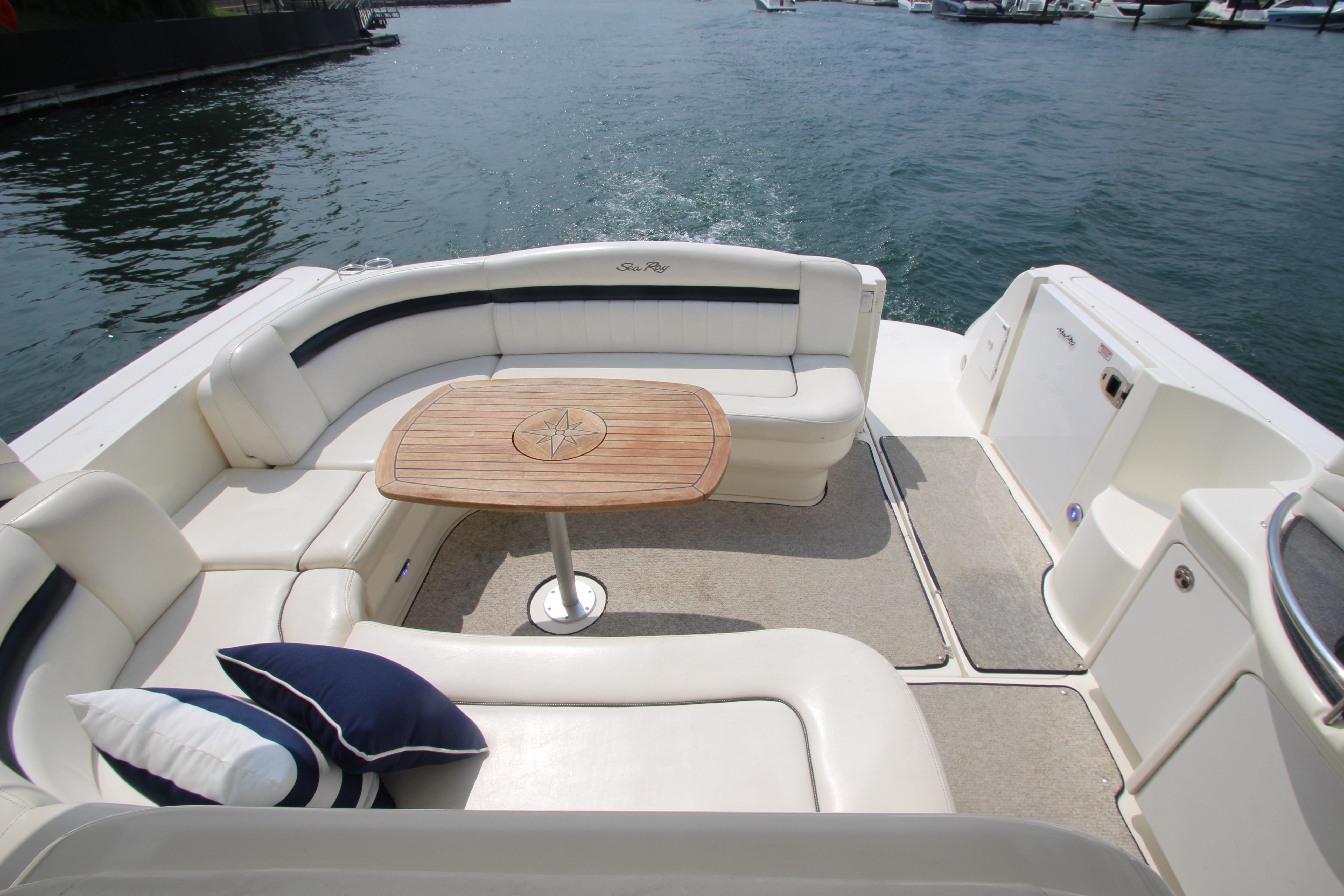 2004 Sea Ray 40 Sundancer boat with cushioned seating and wooden table on deck.