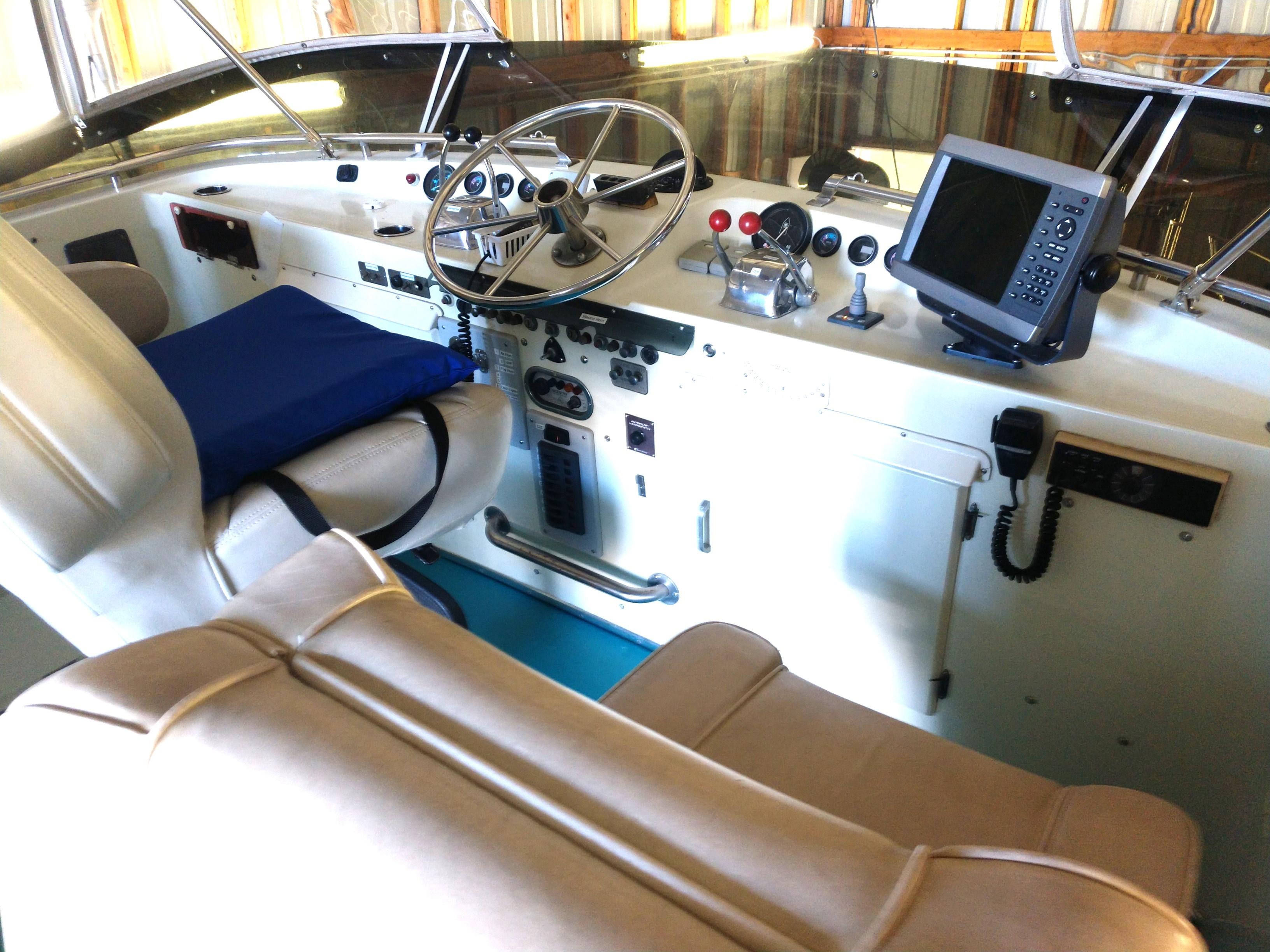 1981 Tollycraft 43 Motoryacht helm with steering wheel, navigation equipment, and cushioned seating.