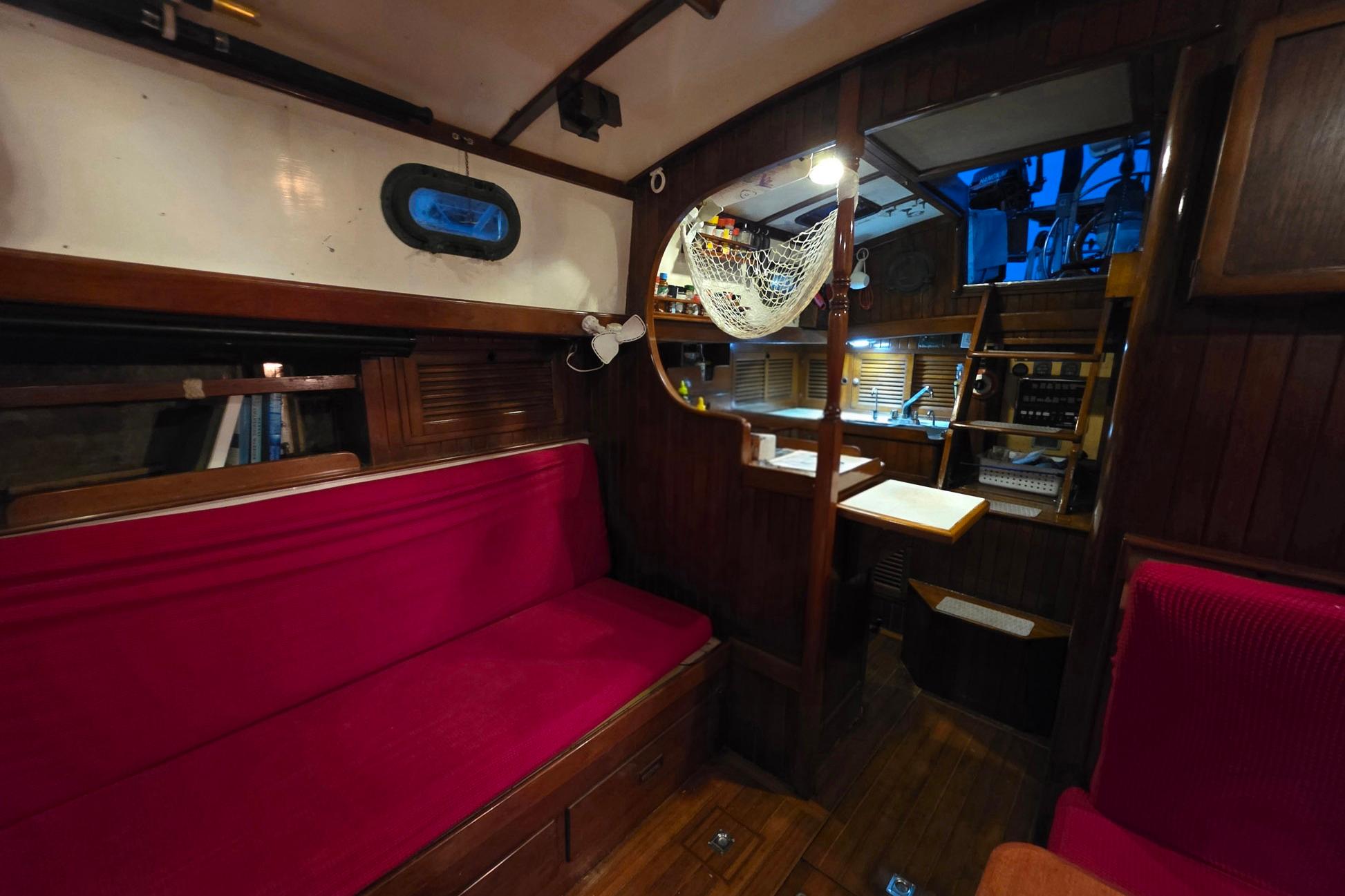 Interior of 1982 Tayana 37 sailboat with red seating and wooden cabinetry.