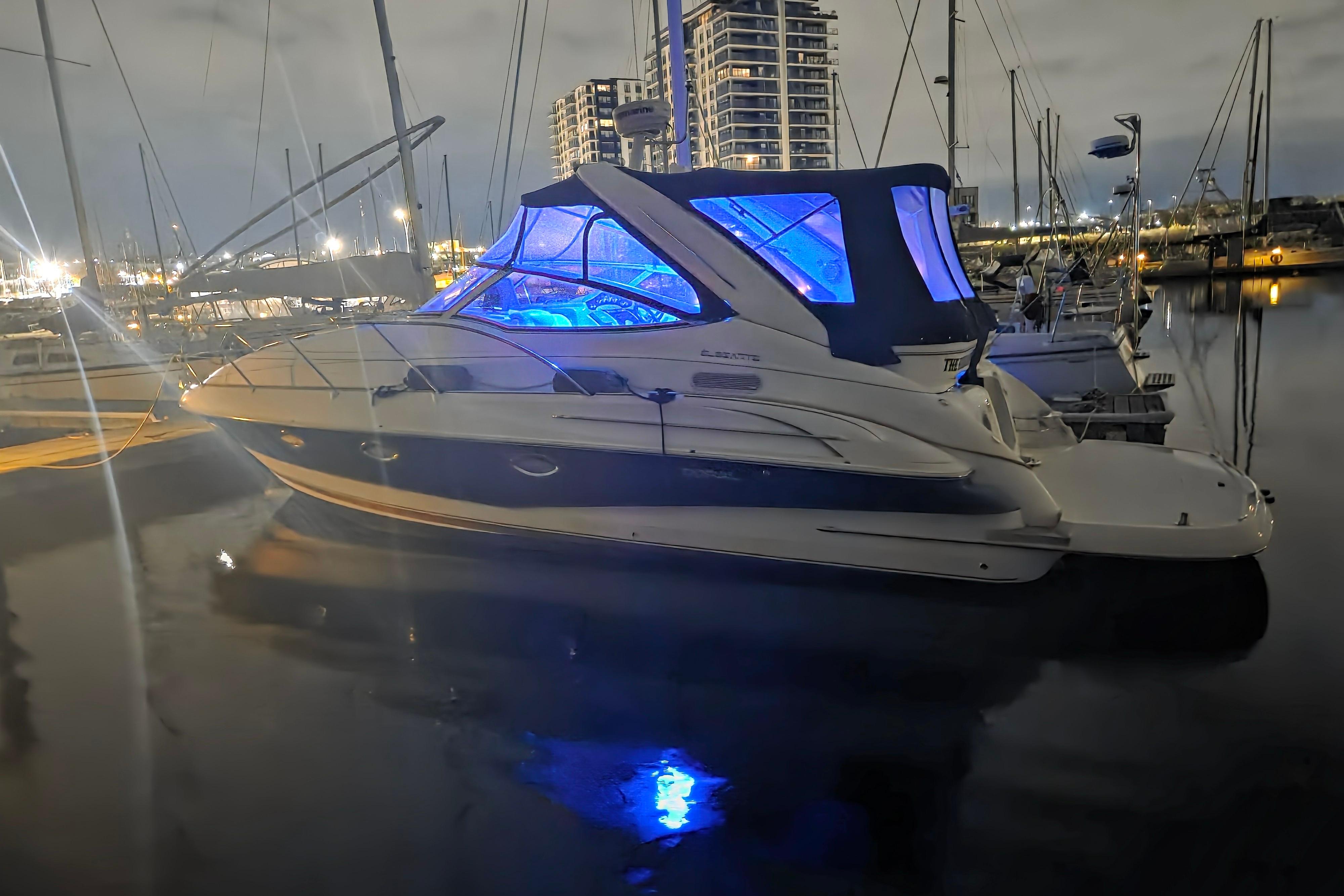 2005 Doral Elegante boat docked at night with blue interior lighting.