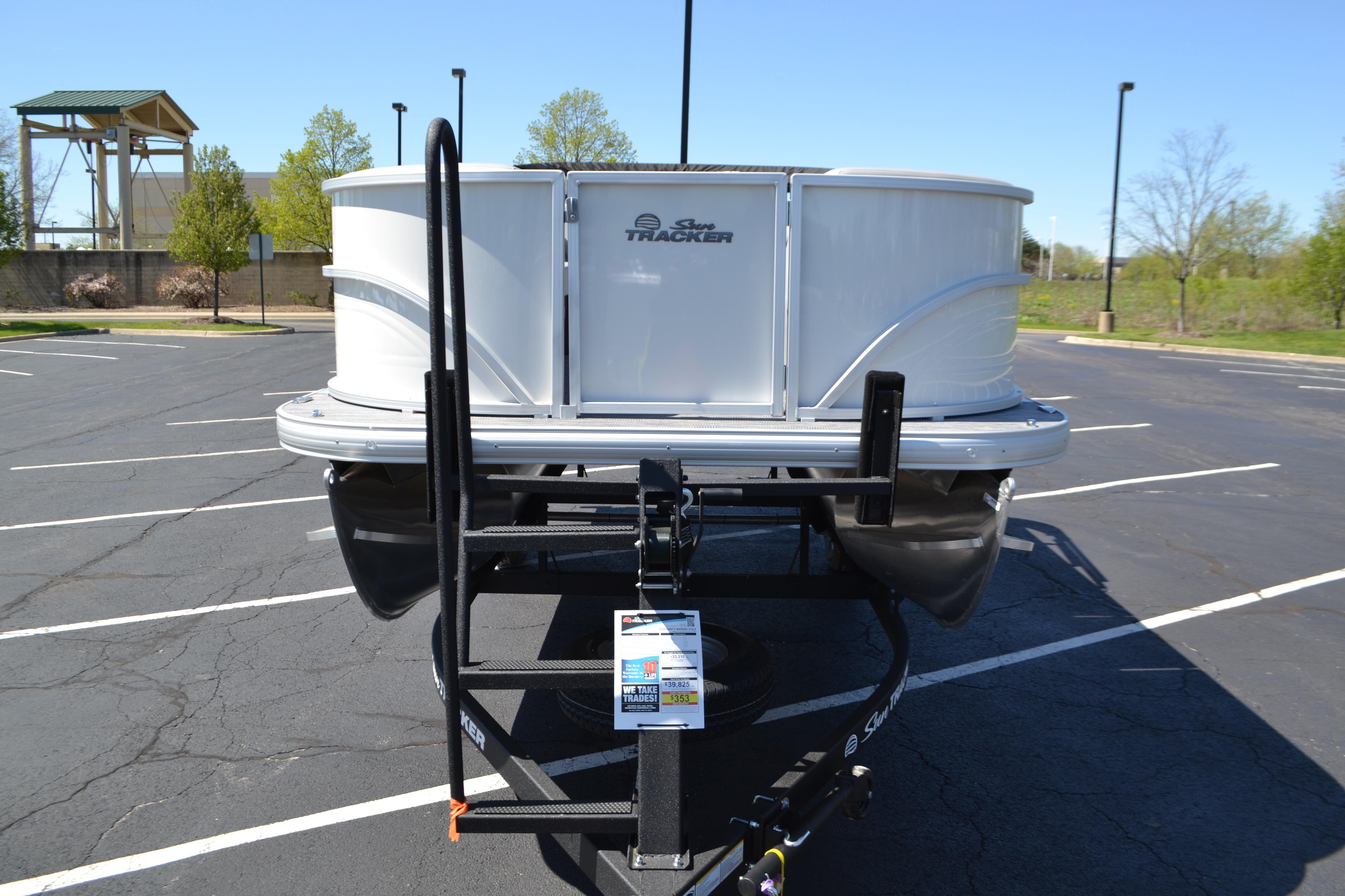 2026 Sun Tracker Party Barge 18 DLX pontoon boat on trailer in parking lot.