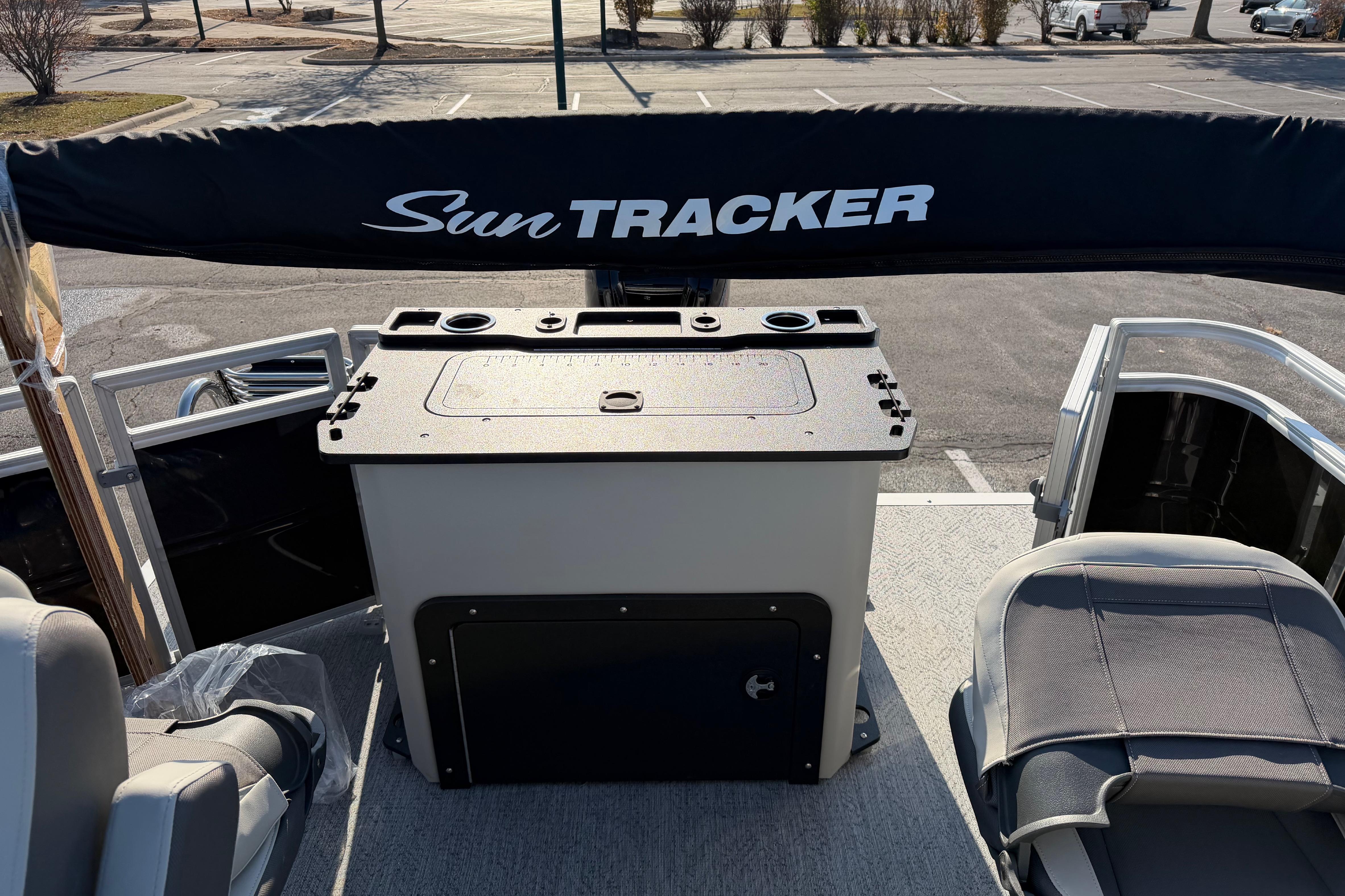 2026 Sun Tracker Fishin' Barge 20 DLX interior with seating and storage, parked outdoors.