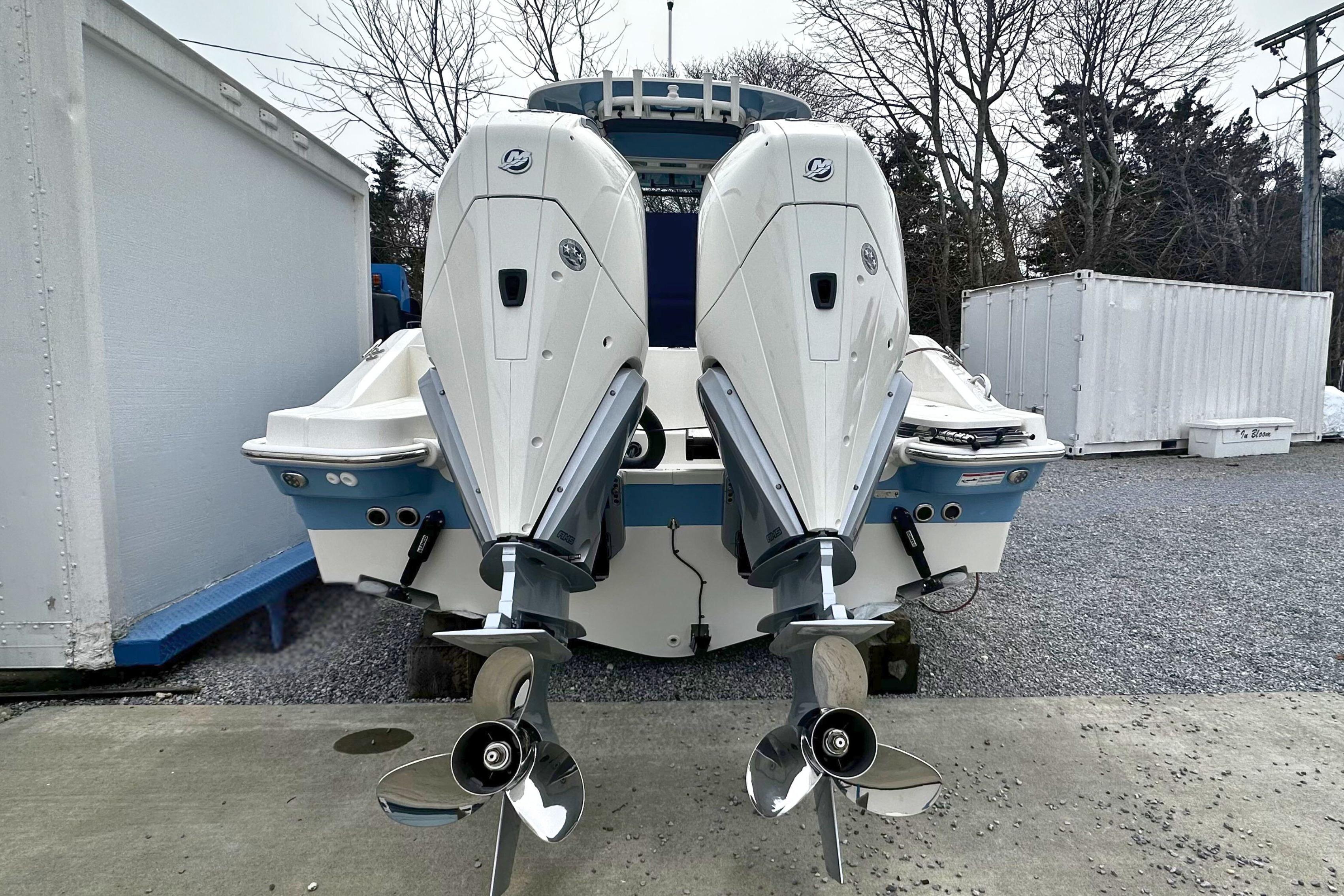 2026 Boston Whaler 280 Dauntless with dual outboard engines, parked on gravel.