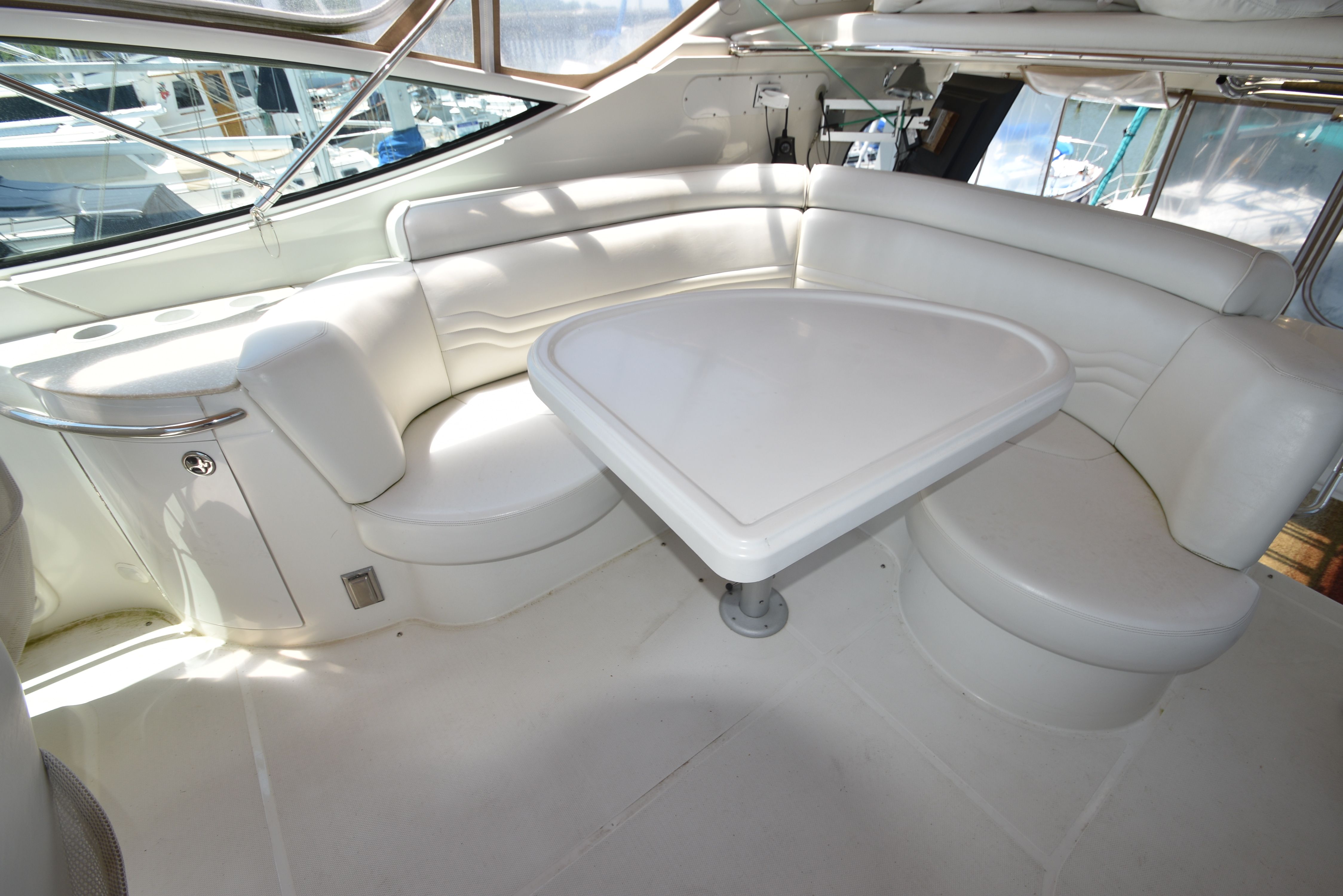 Interior view of a luxury yacht with a white triangular table and cushioned seating.