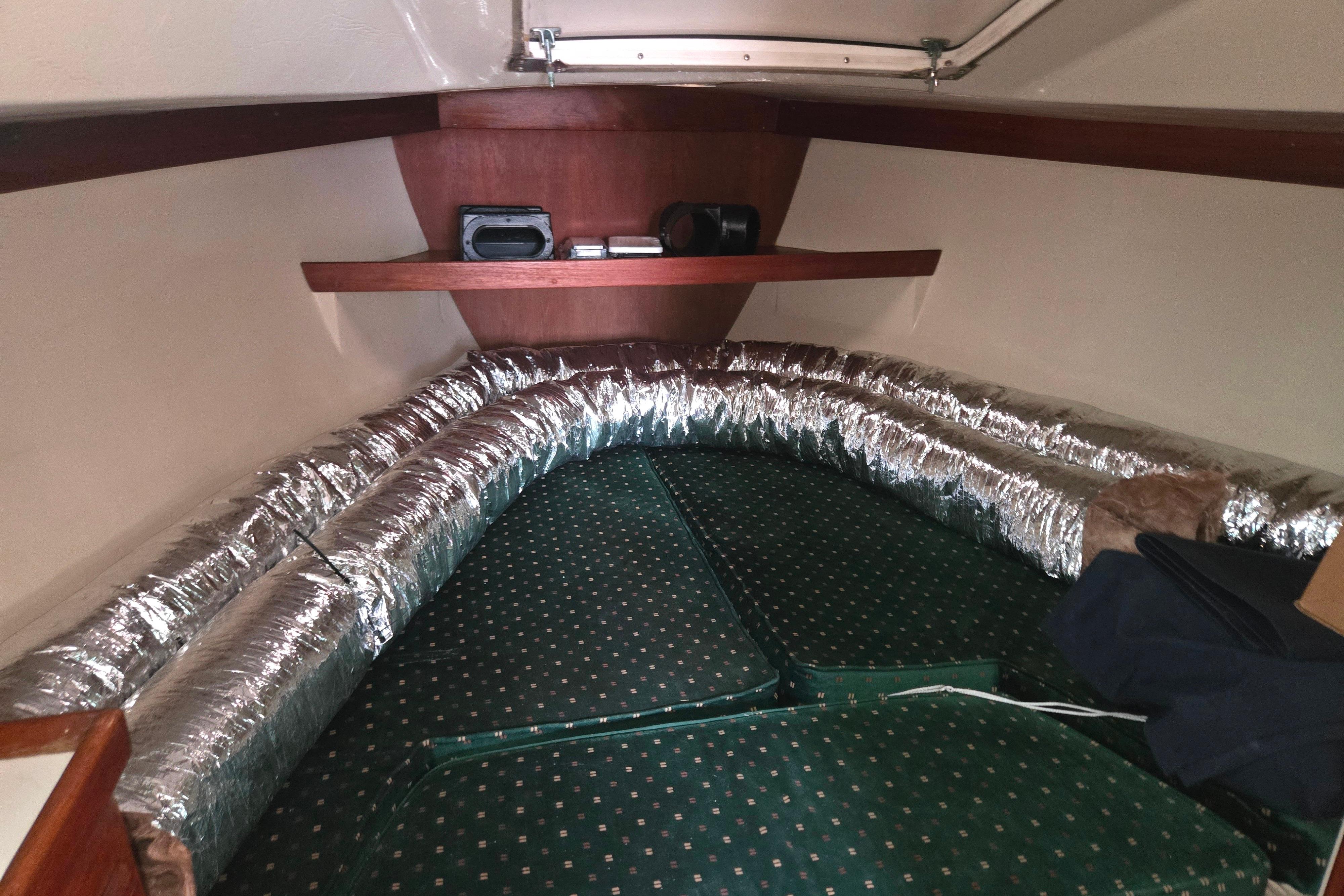 Interior cabin of a 1986 Catalina 355 sailboat with green cushions and silver insulation.