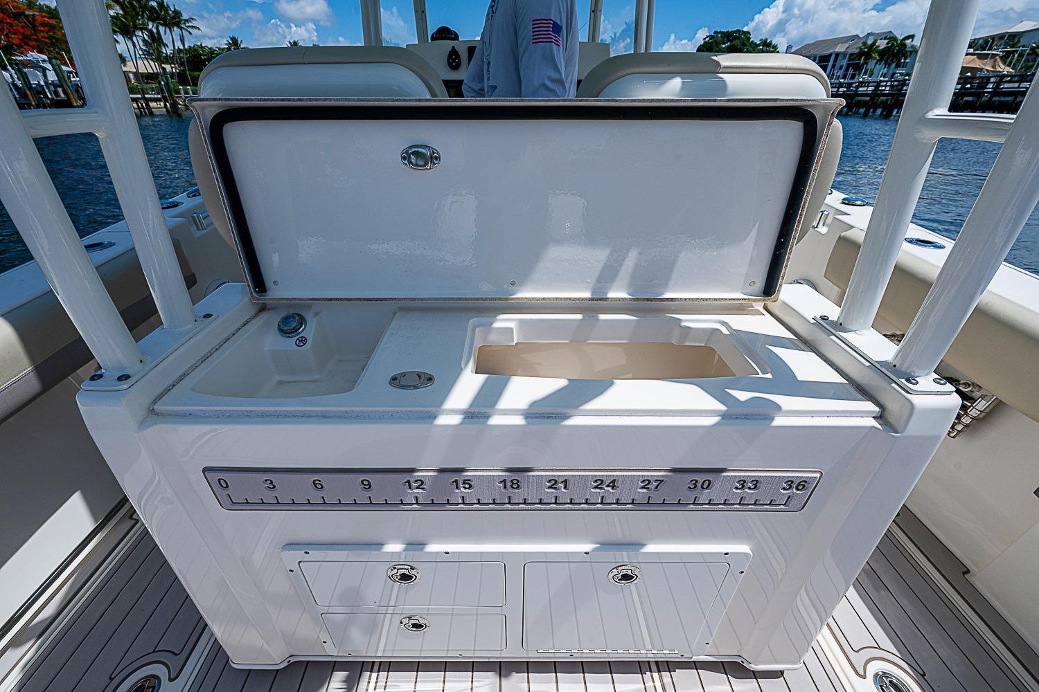 2019 Cobia 320 Center Console boat with open storage compartment and sink on deck.