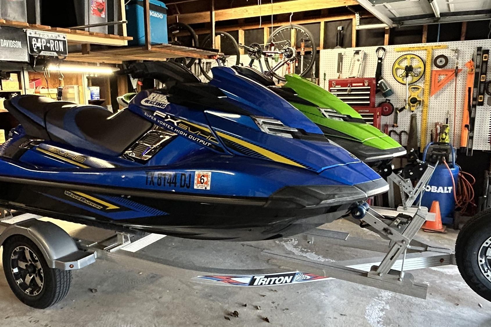2017 Yamaha WaveRunner FX Cruiser SVHO in a garage, blue and green models on a trailer.