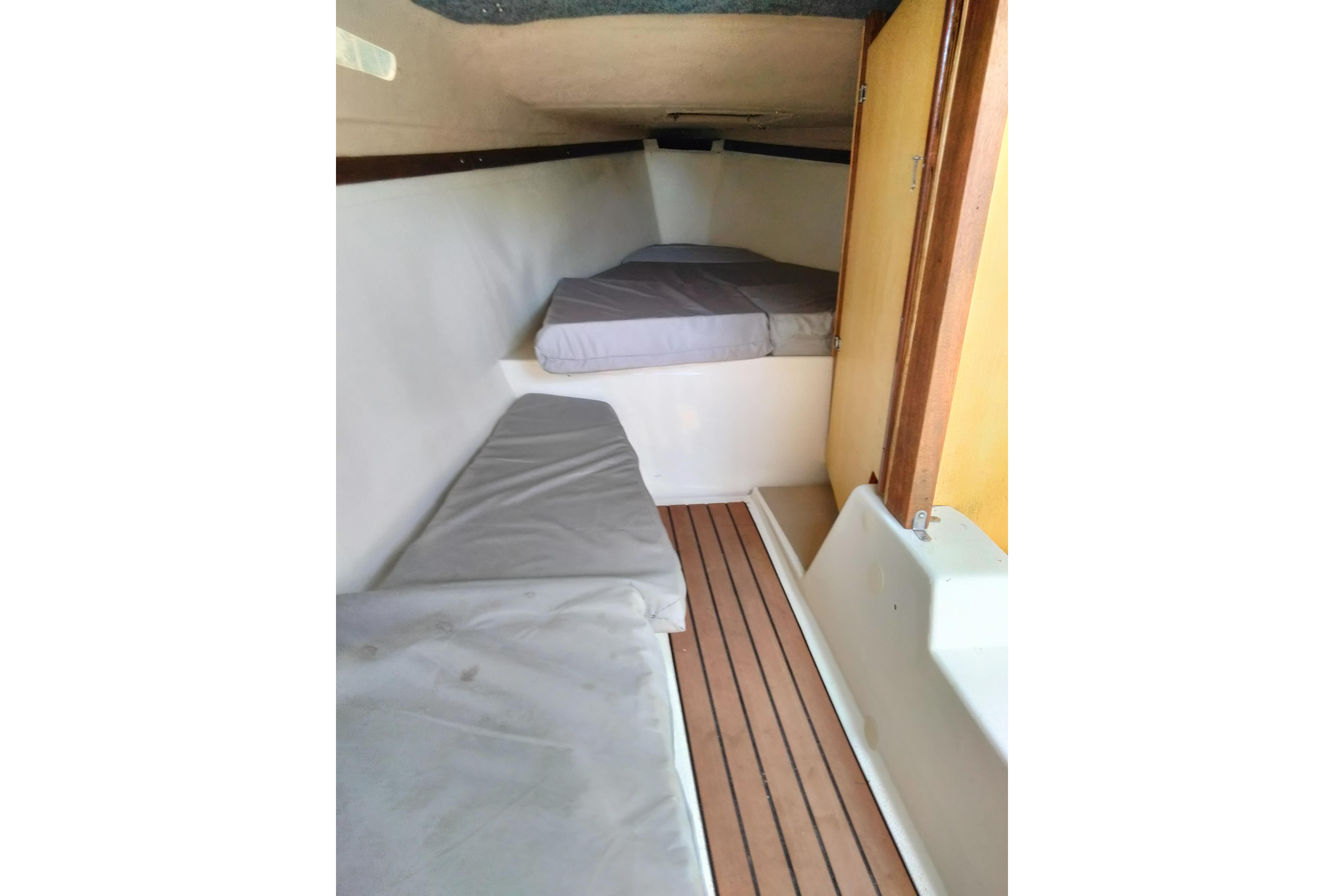 Interior cabin of a 1980 MacGregor 25 sailboat with cushioned seating and wooden flooring.