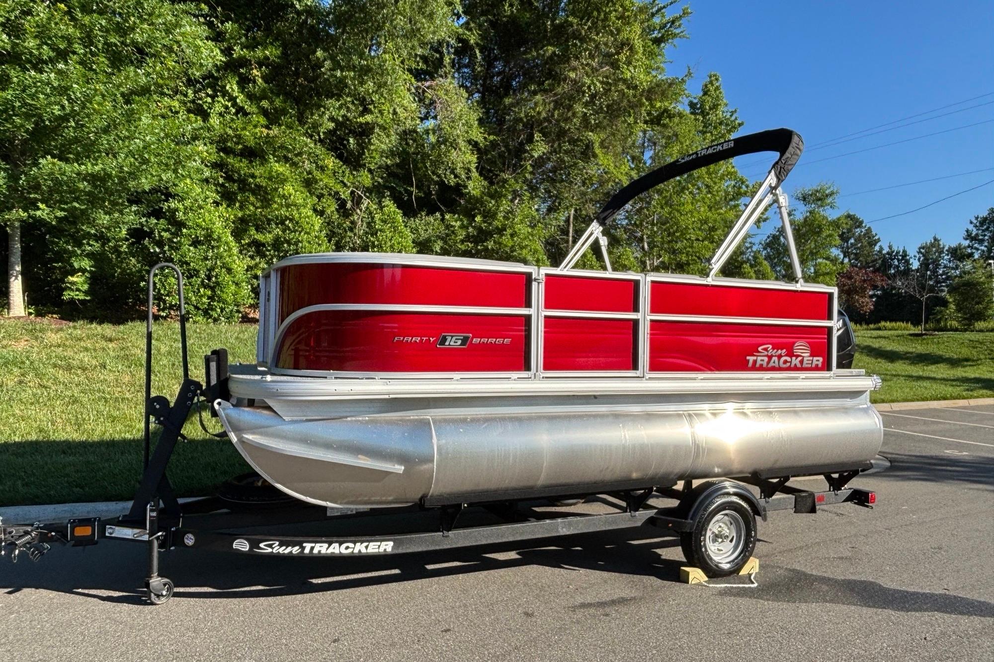 2026 Sun Tracker Party Barge 16 DLX pontoon boat on trailer, parked outdoors.
