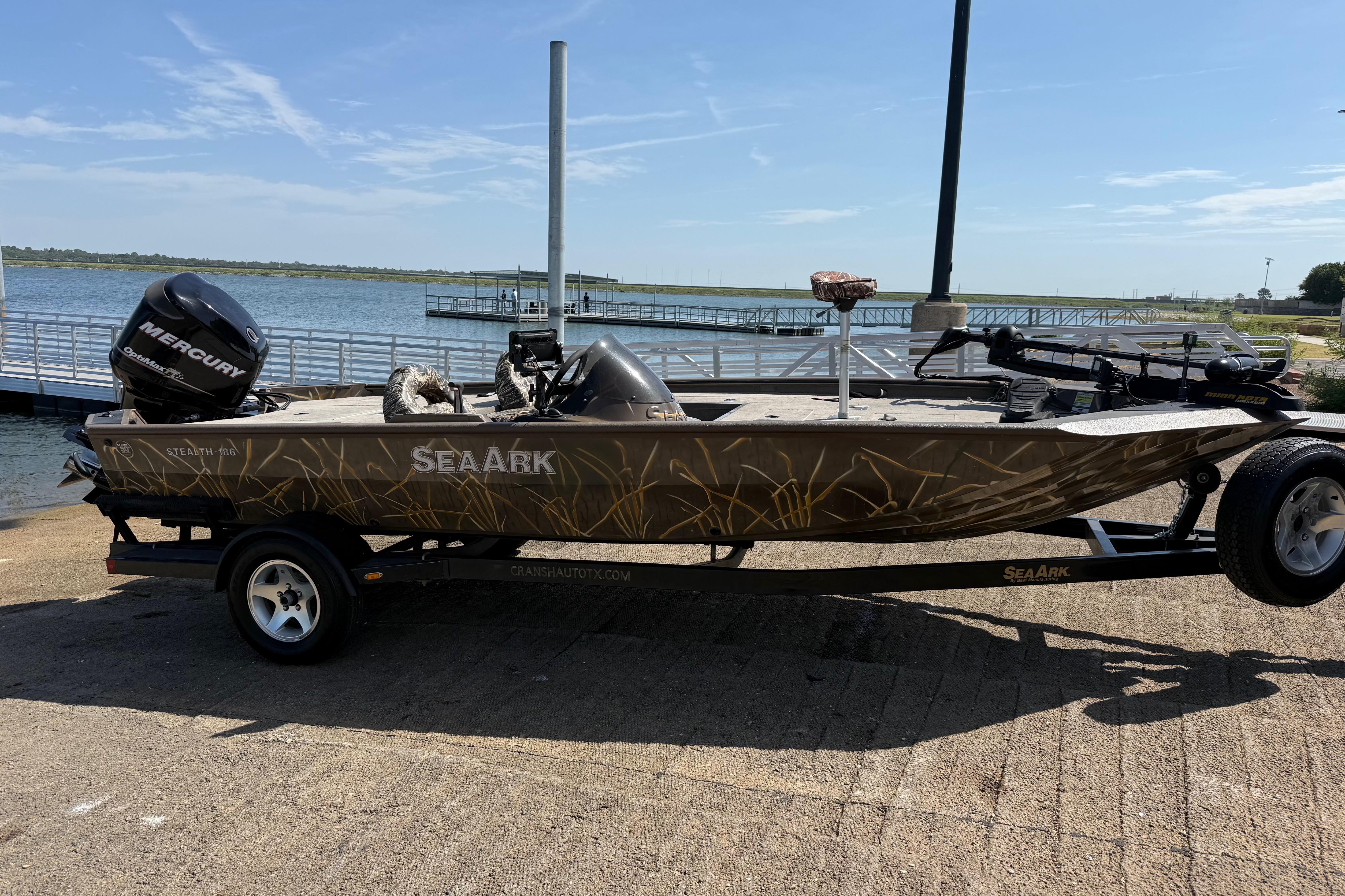 2010 SeaArk Stealth 190 boat with Mercury outboard motor on trailer by a lake.