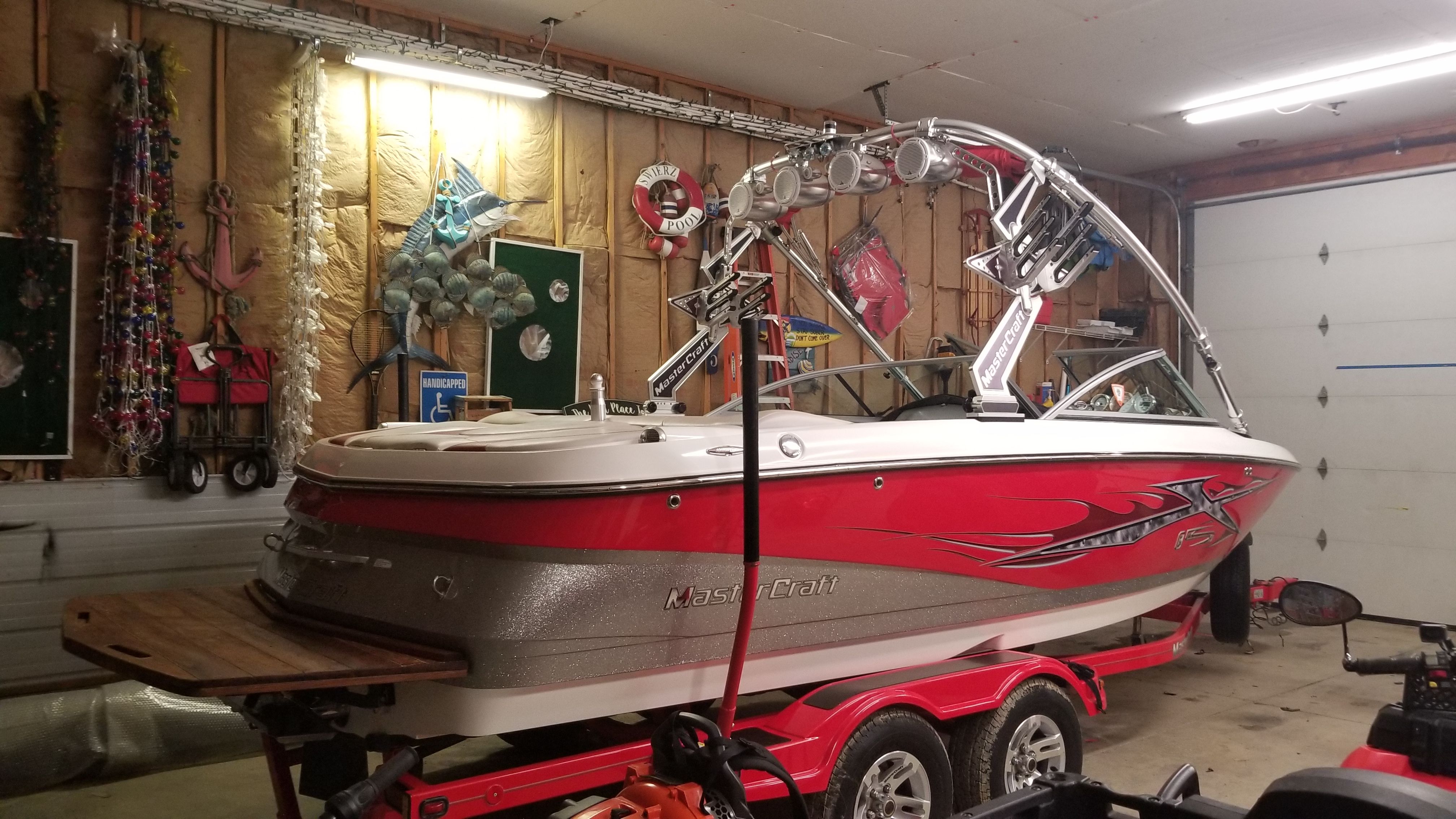 2007 MasterCraft X-15 boat in garage with red trailer.