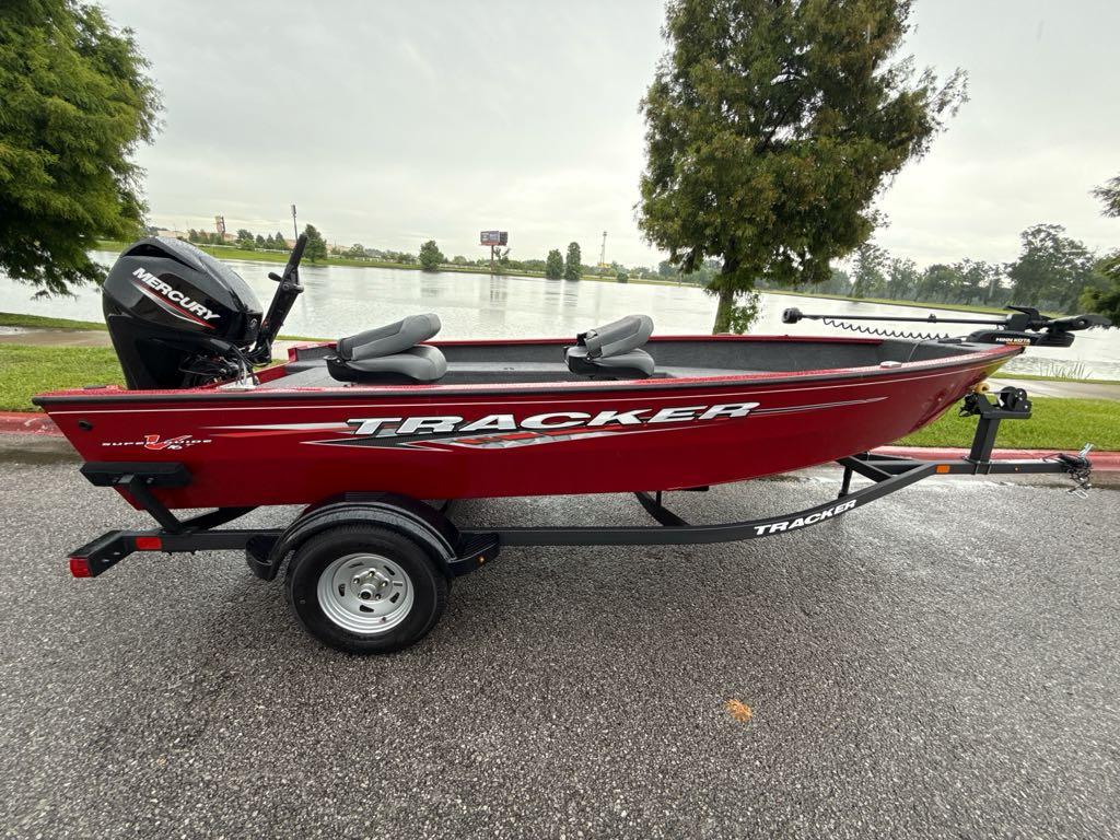 2025 Tracker Super Guide V-16 T boat on trailer by a lake.