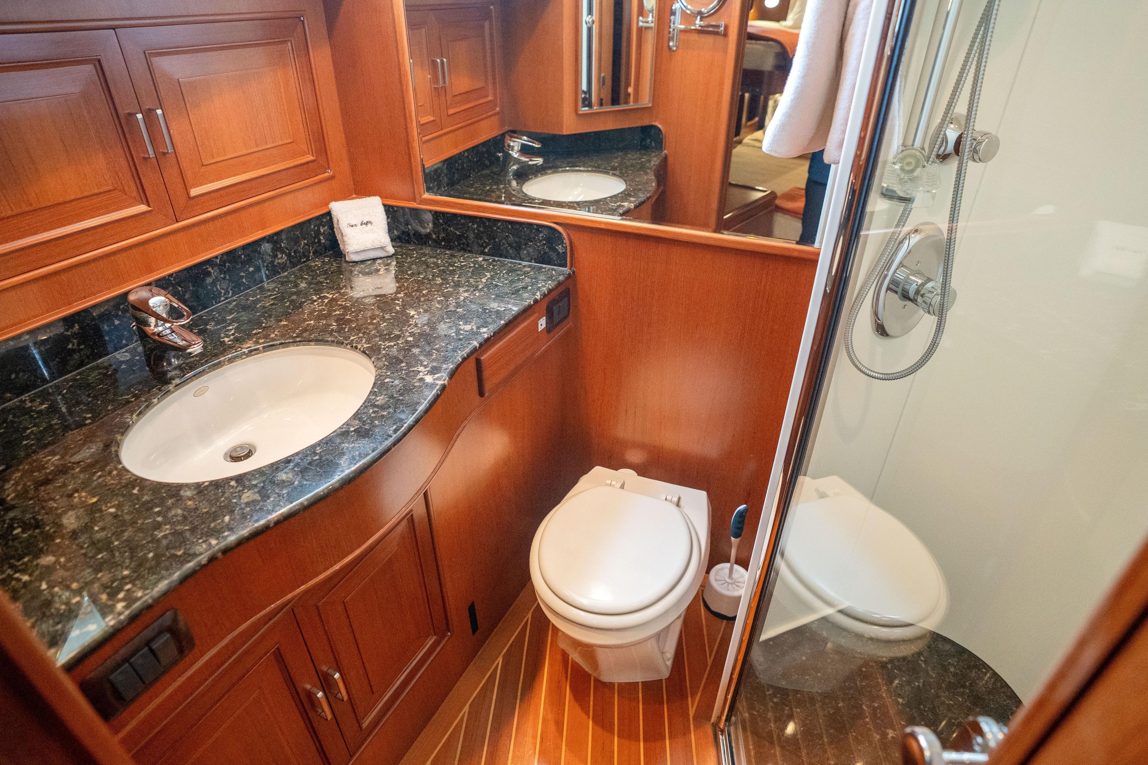 Luxurious 2006 Fleming 75 yacht bathroom with wood cabinetry and marble countertop.