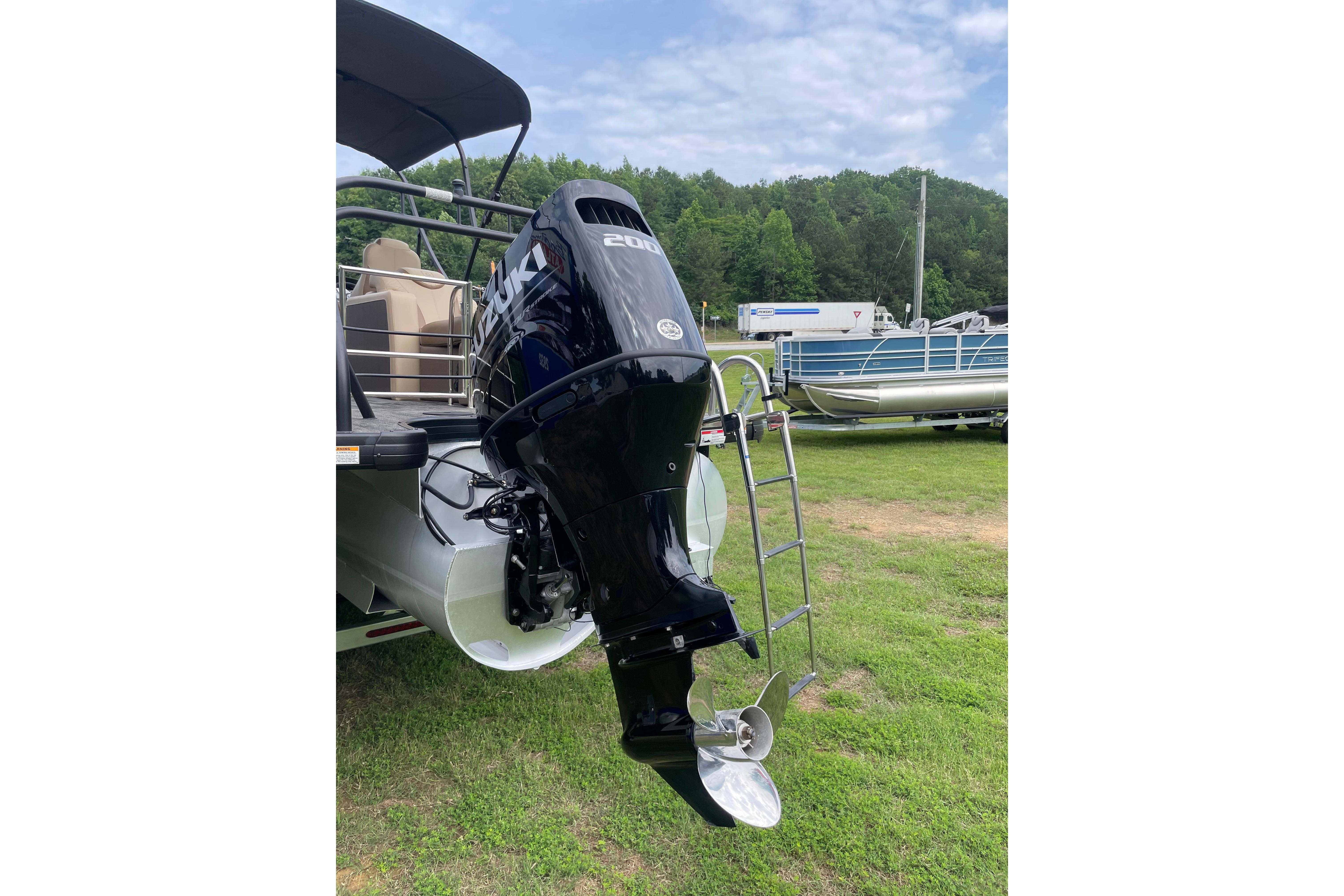 2024 Godfrey Monaco 235 SB boat with Suzuki outboard motor on grassy area.