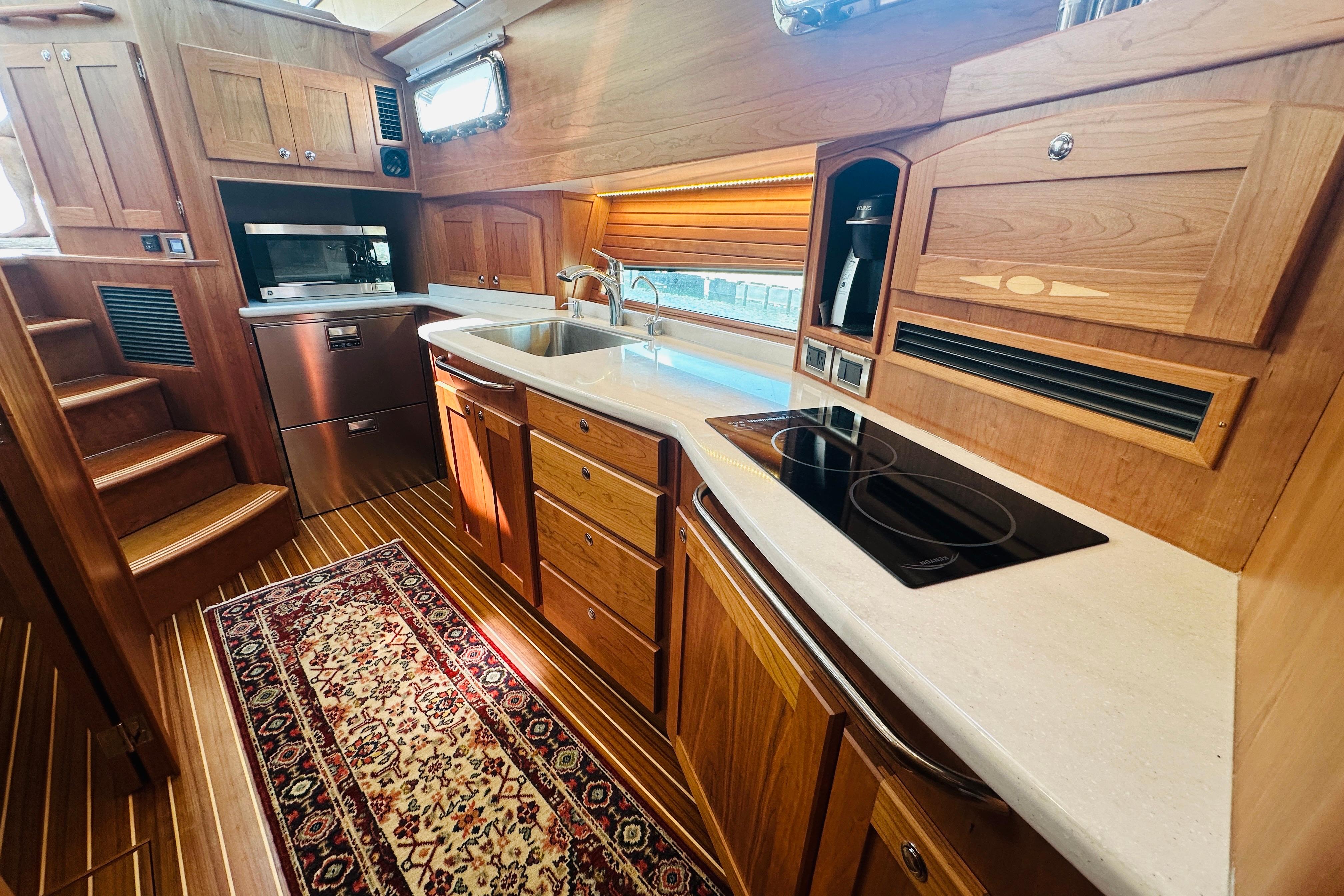 Luxurious 2025 Sabre 48 Salon Express yacht kitchen with wood cabinetry and modern appliances.