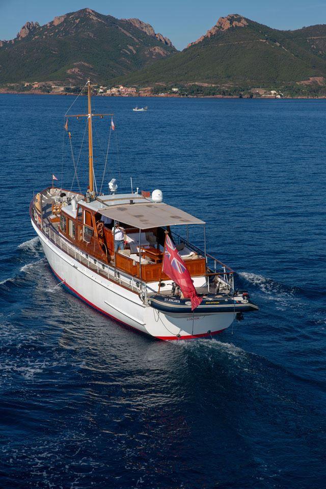Vintage 1958 Feadship Custom 25m yacht cruising in scenic coastal waters.
