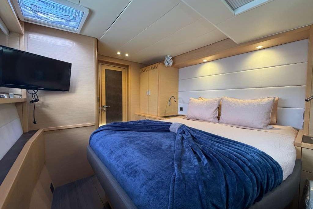Luxurious cabin interior of 2019 Lagoon 630 MY yacht with cozy bed and TV.