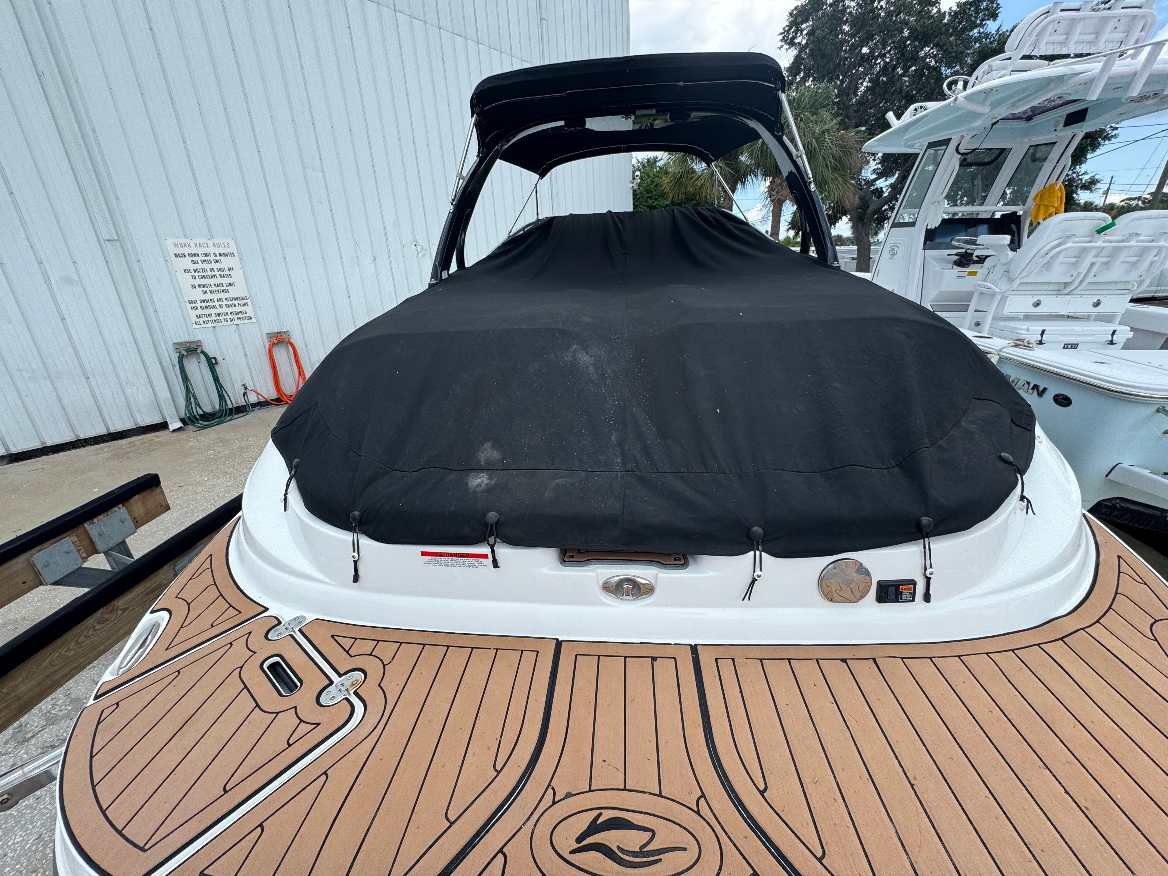 2017 Rinker QX29 BR boat with black cover at dock.