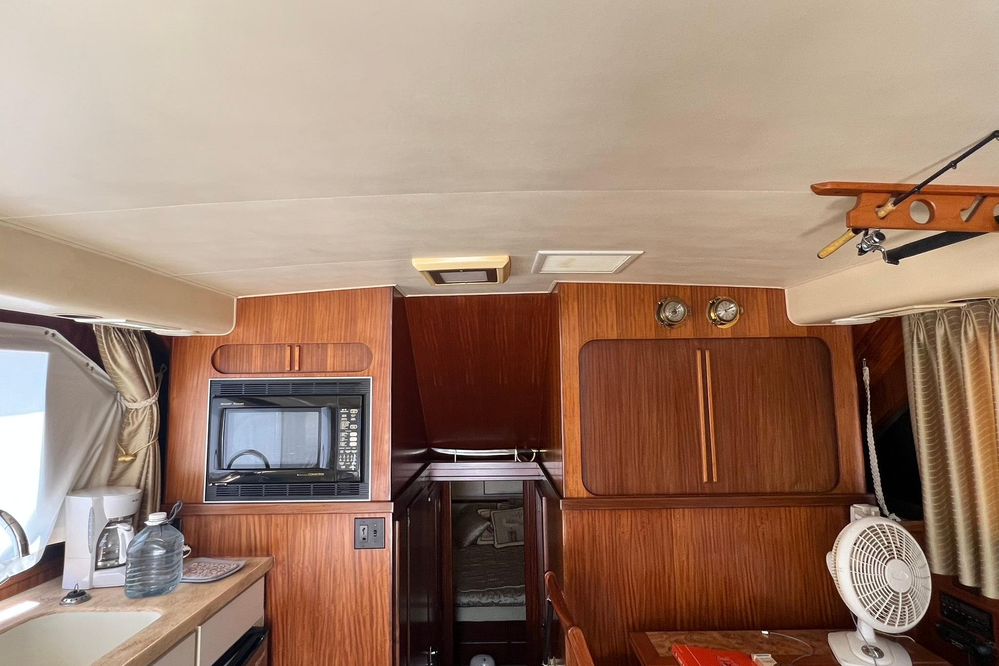 Interior of a 1990 Hatteras 41 Convertible yacht with wood paneling and kitchen amenities.